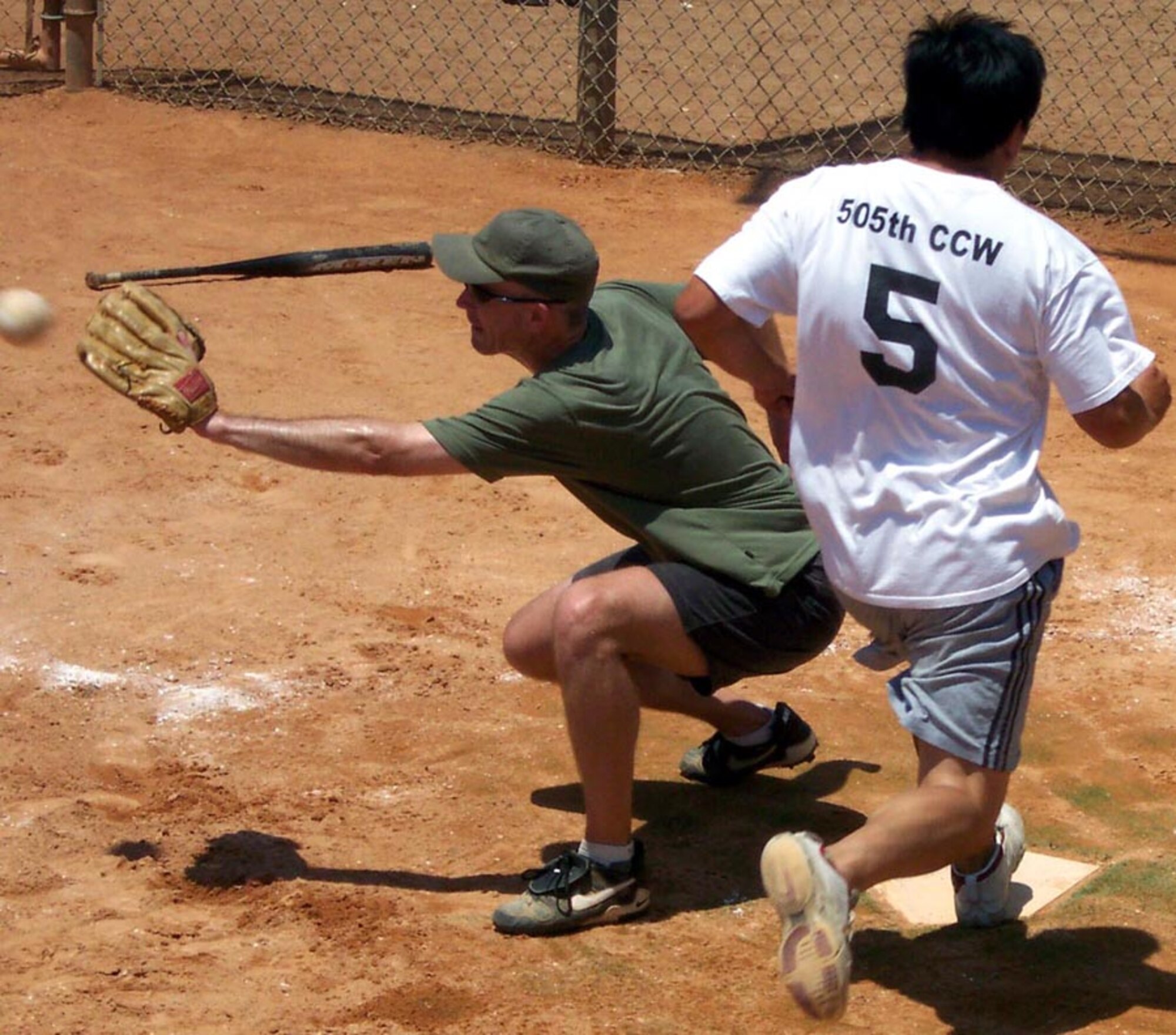 Jim Hoy, 505th Command and Control Wing, beats the throw to home as catcher Keith Schlechte, Air Force Special Operations Command, waits for the ball. This is the third year in a row the 505th CCW team has won the Over 30 softball tournament . (U.S. Air Force photo by Staff Sgt. Haldon Marmolejos)