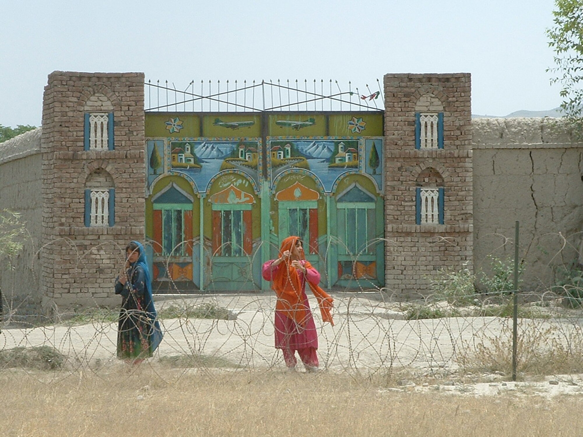 Two Afghan children linger near concertina wire after they are given candy by Master Sgt. David Wilburn and other troops on patrol there in 2003. (Courtesy photo) 