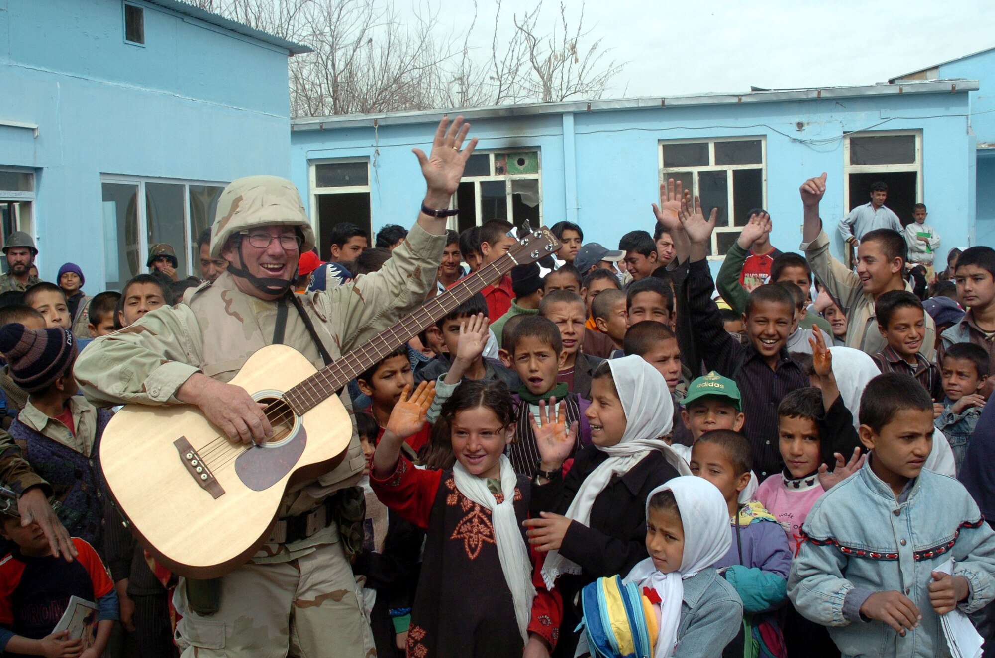 Tech. Sgt. David Foster meets with the local Afghan children June 11 after a performance with the Air Force band "Max Impact" near Camp Alamo, Afghanistan. Sergeant Foster is a guitarist with the band. (U.S. Air Force photo/Master Sgt. Regina Coonrod)