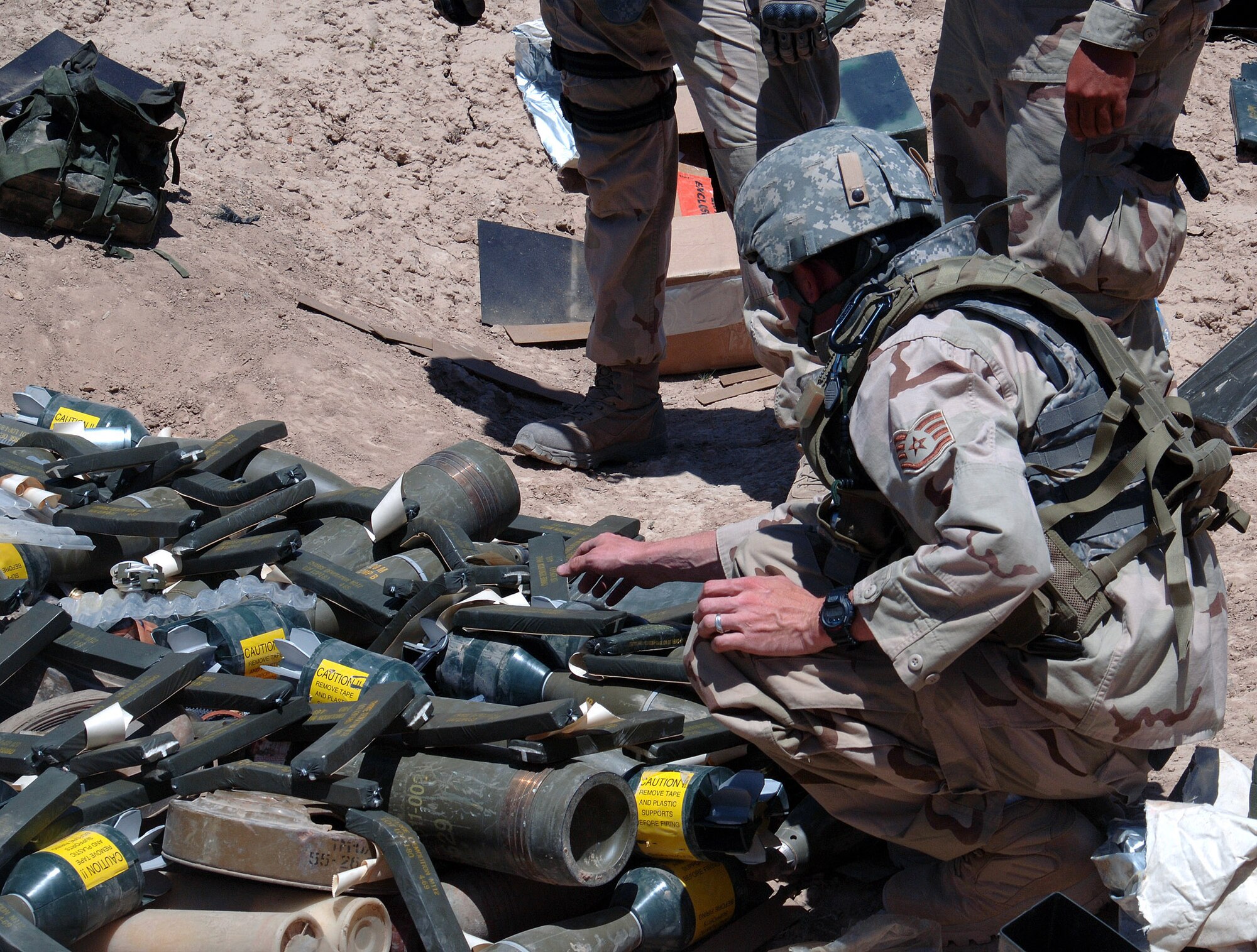 Staff Sgt. Rick Palmar, 455th Expeditionary Explosive Ordnance Disposal assistant team lead, carefully places C-4 explosives on top of more than 1,000 pounds of stored munitions, mines and weapons caches for a controlled detonation outside of Bagram Airfield, Afghanistan June 13. (photo by Staff Sgt. Craig Seals)