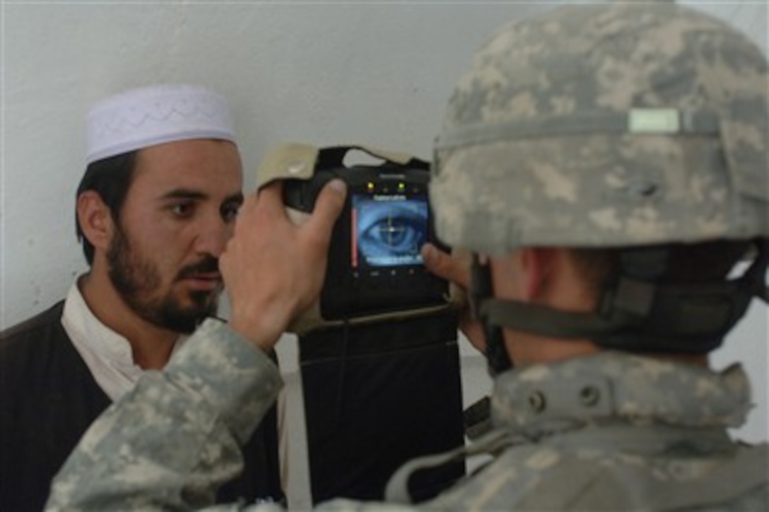 U.S. Army Pfc. Arthur Wallace uses a handheld interagency identity detection equipment system to gather identification information from an Iraqi man in Mostowfi, Afghanistan, on June 1, 2007.  Wallace is attached to Delta Company, 2nd Battalion, 508th Parachute Infantry Regiment.  