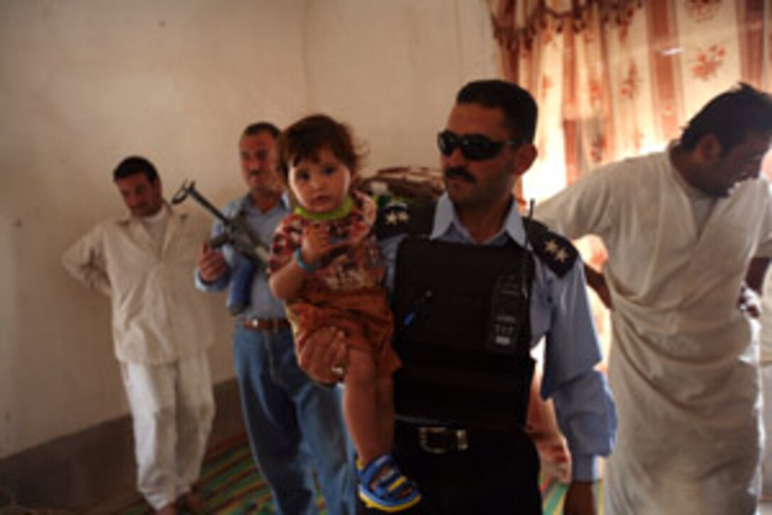 An Iraqi Police officer holds a child after giving her a piece of candy while on patrol. The IPs have been working closely with Marines from Weapons Company, 3rd Battalion, 6th Marine Regiment, to provide a security presence in this area. The IPs are local citizens who are defending their communities. They know the language, the people, and the area, which means they form a formidable team with the Marines.