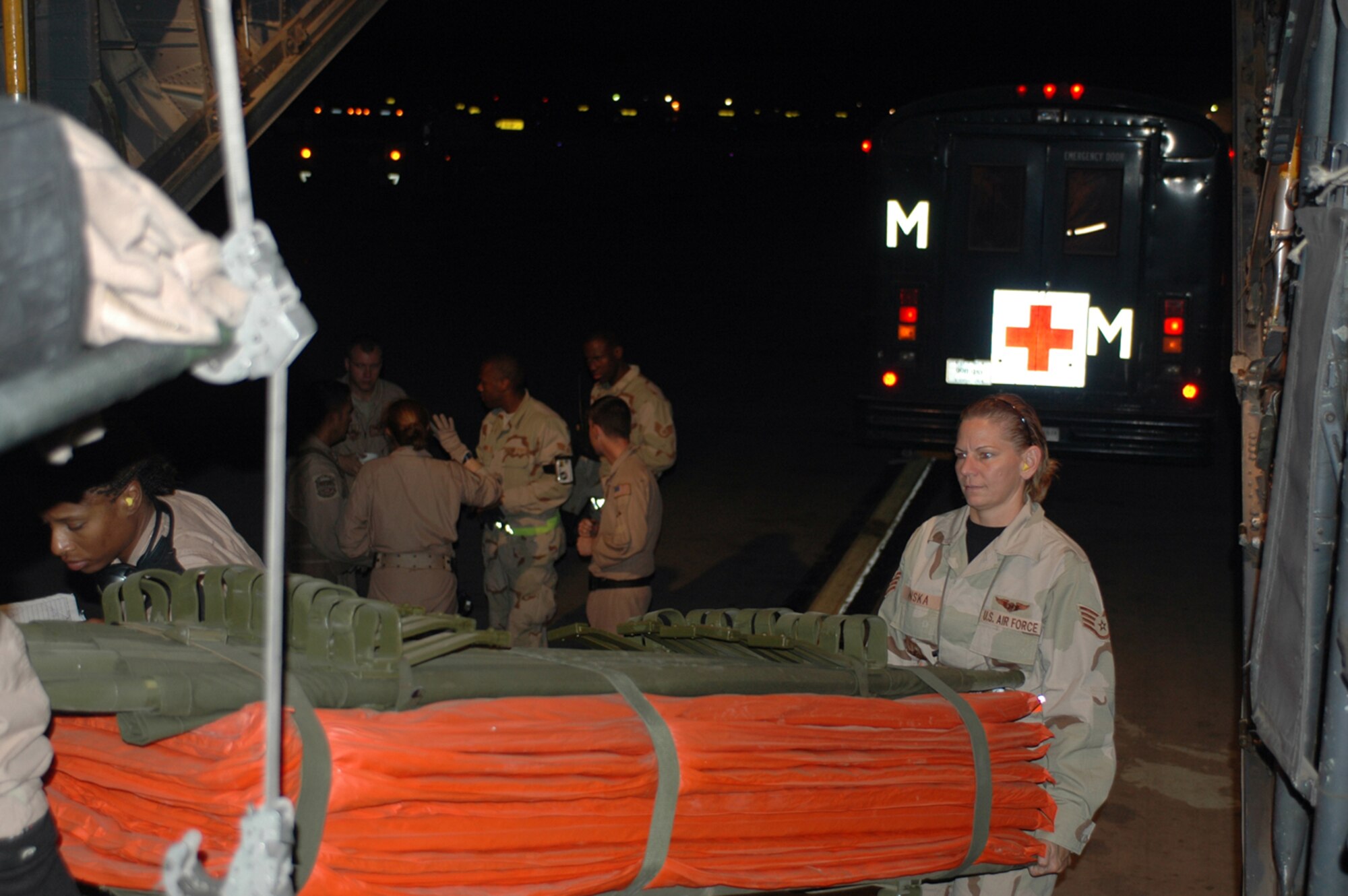 (Right) Staff Sgt. Christine Penska, 332nd Operations Support Squadron, helps (left) Staff Sgt. Christine Hall, 379th Expeditionary Aeromedical Evacuation Squadron, unload a litter to transport patients from the tarmac to the C-130 aircraft. Patients were sent to a base in Southwest Asia for further care. (U.S. Air Force photo by Staff Sgt. Cassandra Locke)