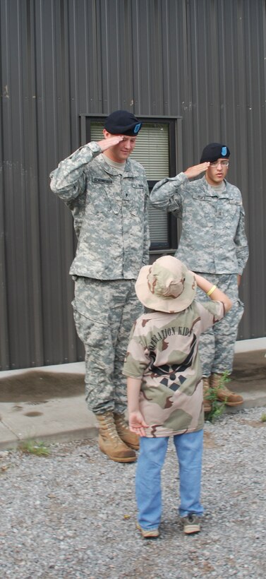 Operation Kids Investigating Deployment Services chalk one commander Garrett Brown, son of Master Sgt. Michael Brown, returns the salute of Specialist Damion Schinnerer and Private First Class Joshua Cliff, both from Delta Company 264th Medical Battalion. (U.S. Air Force photo/Airman 1st Class Jacob Corbin)