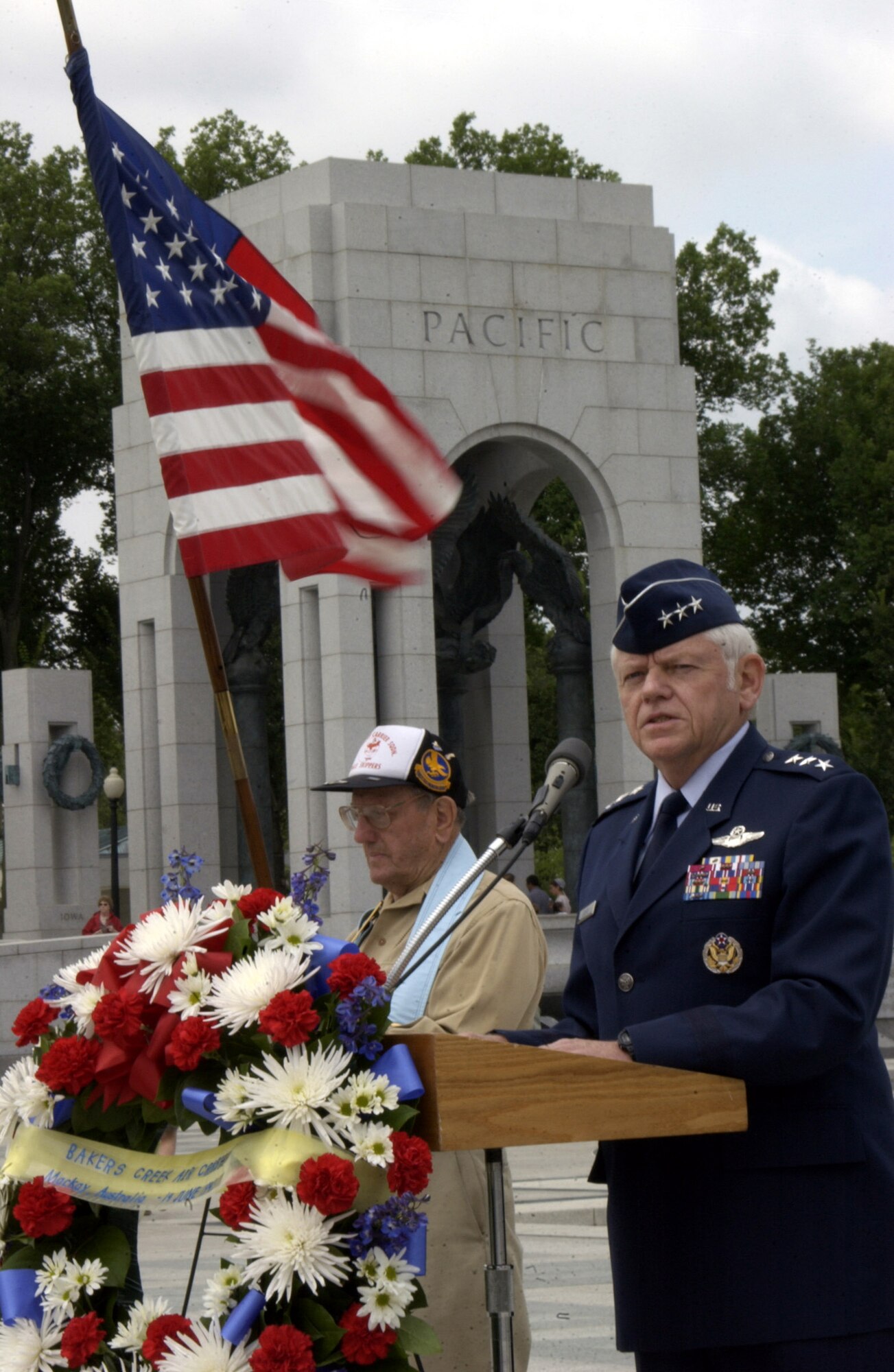 At a ceremony at the World War II Memorial June 14 in Washington D.C., Lt. Gen. Arthur Lichte, Air Force assistant vice chief of staff, recounted the Bakers Creek air crash in Australia in June 1943 where 40 American servicemembers lost their lives.  The ceremony here commemorated the 64th anniversary of the crash.  Holding the American flag is Chester Kanach, a former staff sergeant in the Army Air Corps during World War II who was a radio operator in the same unit as the fallen service members.  (U.S. Air Force photo/Staff Sgt. J.G. Buzanowski) 