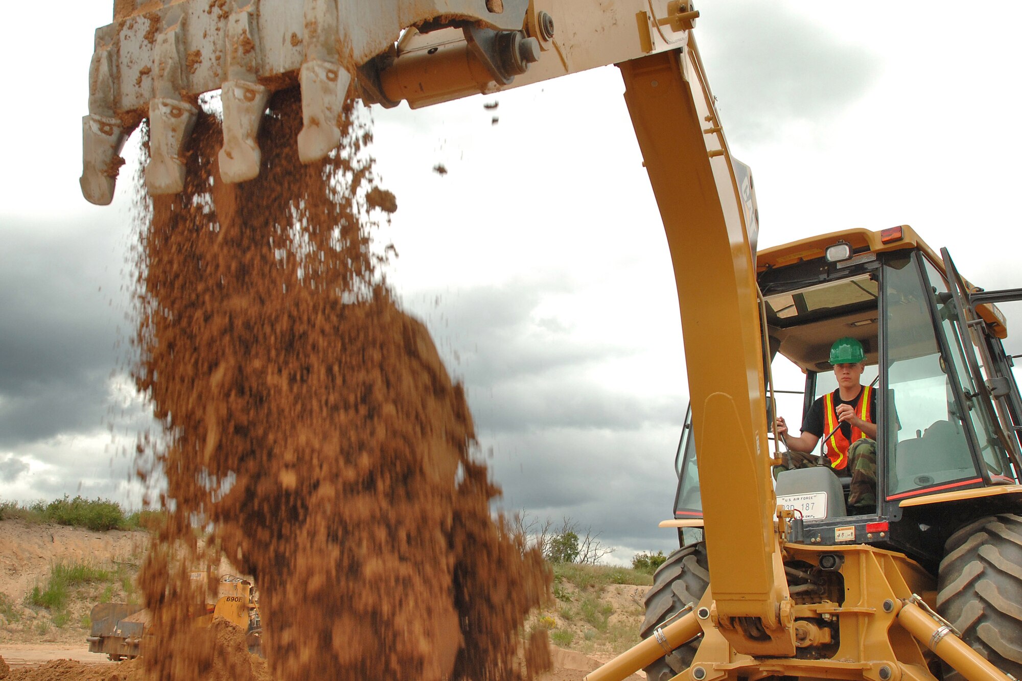 Air Force Academy Cadet 2nd Class Patrick Grandsaert operates a backhoe during the Field Engineering and Readiness Laboratory course at the Academy.  The course exposes cadets to several aspects of civil engineering, including heavy equipment operation, steel bridge construction, designing and pouring concrete beams and paving portions of a road. (U.S. Air Force photo/Joel Strayer)