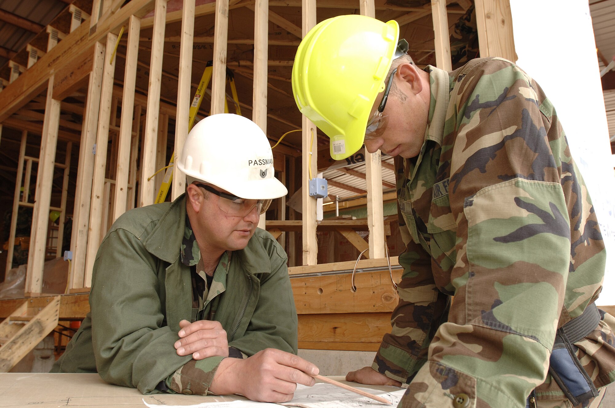 Tech Sgt. James Passman reviews electrical plans with Air Force Academy Cadet 2nd Class Forrest McLain during construction of a house being built by cadets.  The cadets are participating in the Field Engineering and Readiness Laboratory course at the Academy that exposes them to several aspects of civil engineering, including heavy equipment operation, steel bridge construction, designing and pouring concrete beams and paving portions of a road.  Sergeant Passman is with the 5th Civil Engineer Squadron at Minot Air Force Base, N. D. (U.S. Air Force photo/Mike Kaplan)