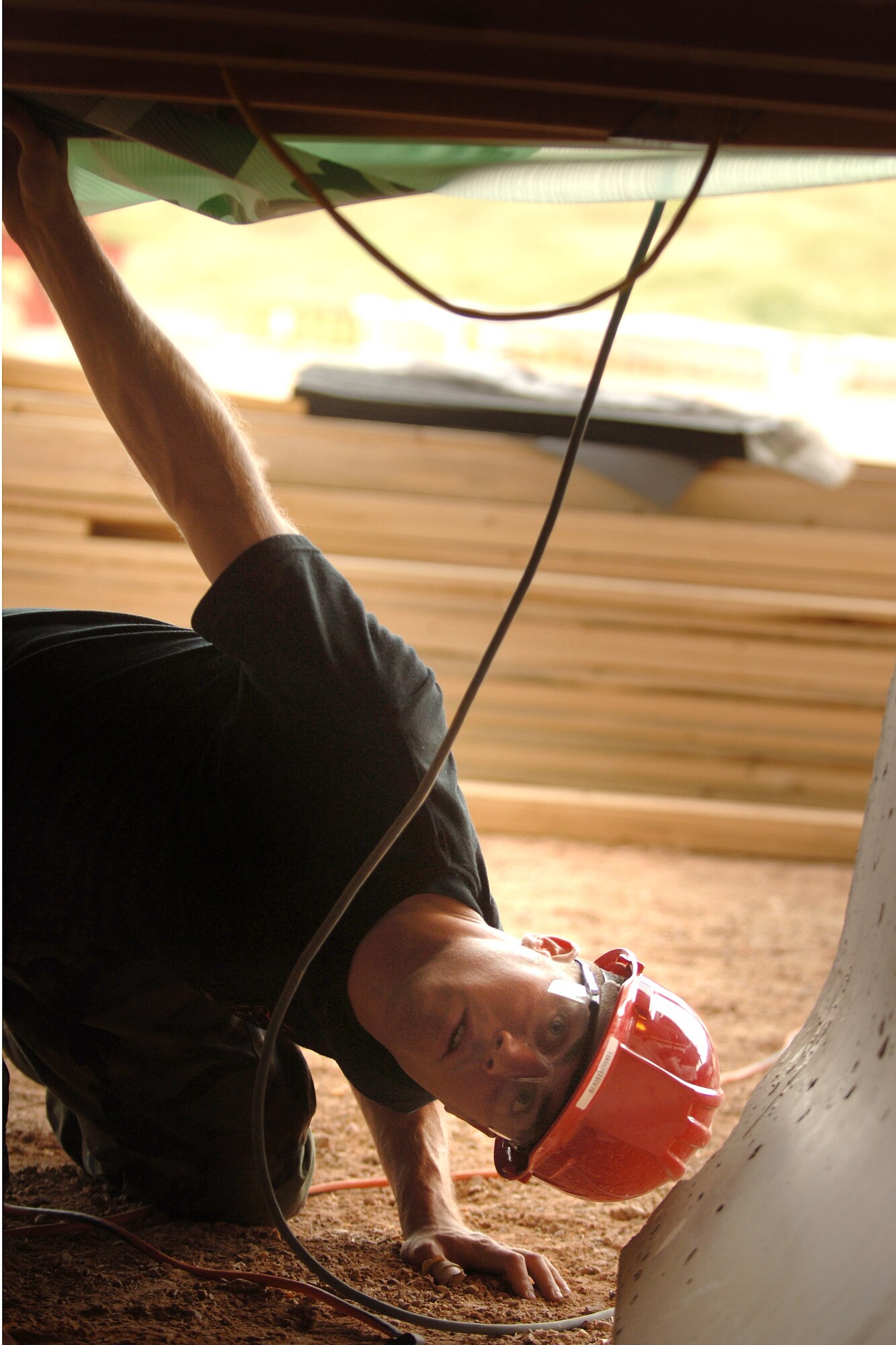 Air Force Academy Cadet 2nd Class Craig Francke checks the routing of electrical cable under a house cadets are building during the Field Engineering and Readiness Laboratory field course at the Academy.  The course exposes cadets to several aspects of civil engineering, including heavy equipment operation, steel bridge construction, designing and pouring concrete beams and paving portions of a road. (U.S. Air Force photo/Joel Strayer)