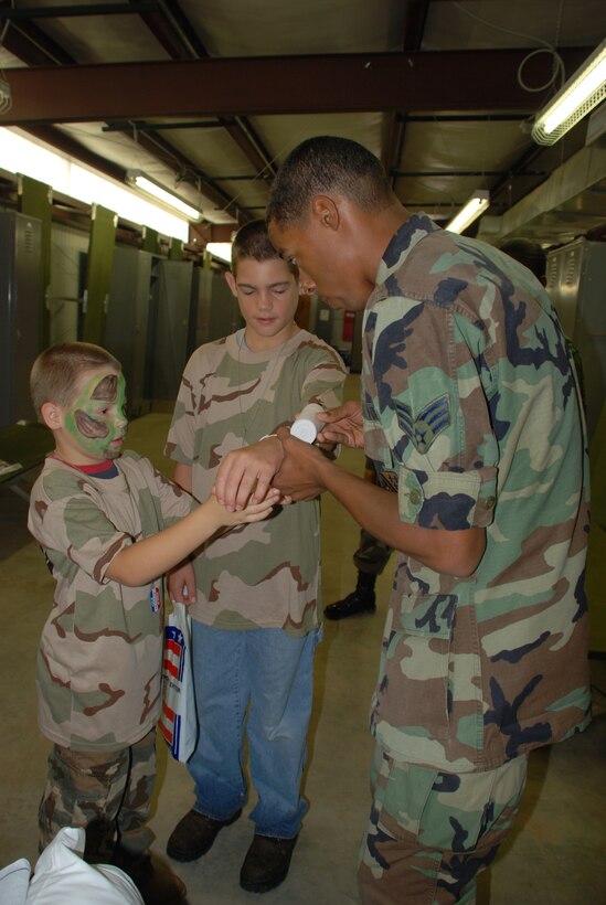 Senior Airman Michael Krueger, a surgical technician with the 82nd Medical Operations Squadron, shows Colton and Terry Clouse, sons of Master Sgt. Timothy Clouse, 82nd Mission Support Squadron first sergeant, how to take care of a broken arm June 16 at Operation Kids Investigating Deployment Services. (U.S. Air Force photo/Airman 1st Class Jacob Corbin)