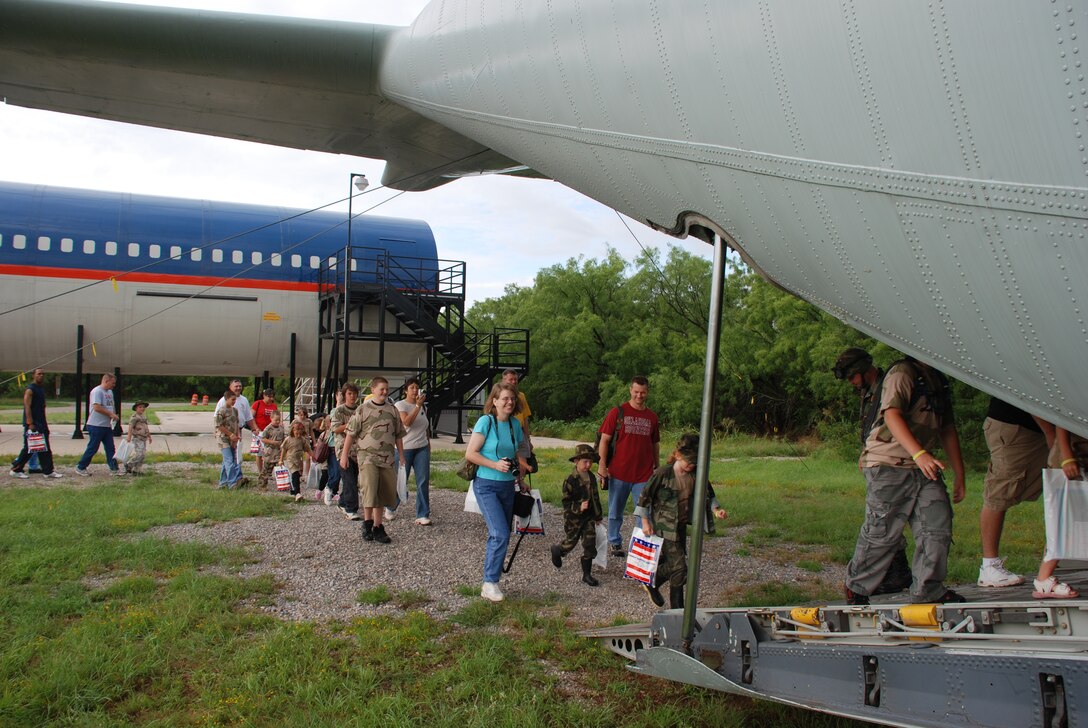 Operation Kids Investigating Deployment Services participants board the C-130 Hercules, one that is minus its wings, that will ferry them to Camp Liberty and their mission June 16. (U.S. Air Force photo/Airman 1st Class Jacob Corbin)