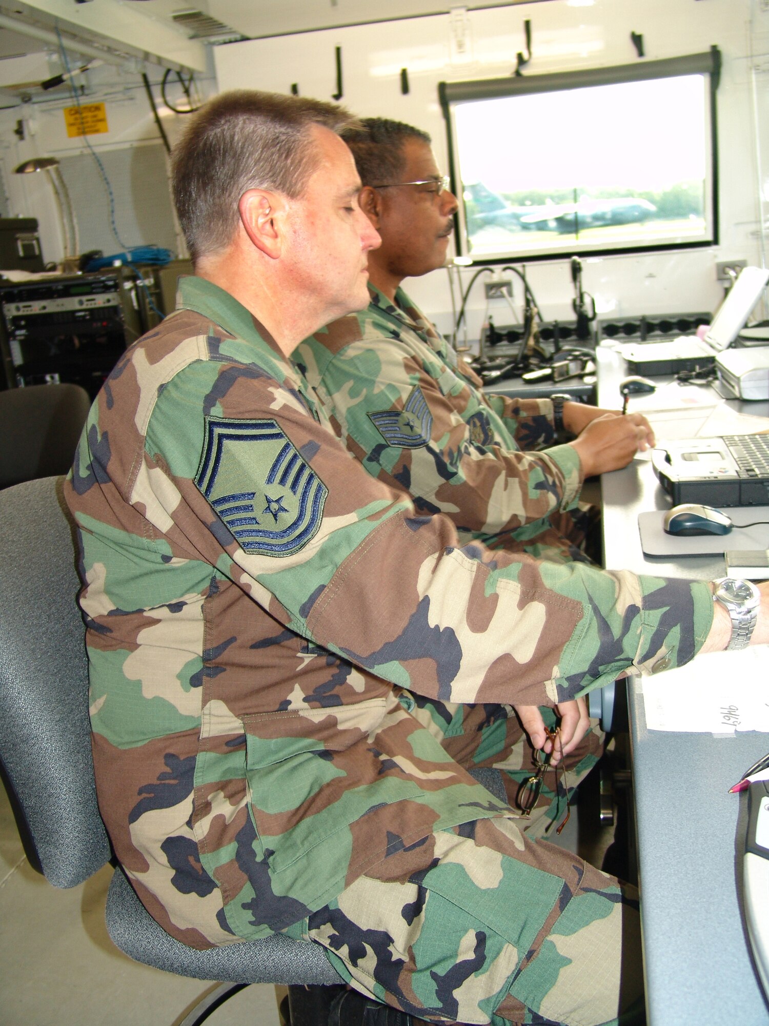 With C-17 dubbed 'Panda 99' passes by the window, Senior Master Sgt. Steve Crook, 94th Airlift Control Flight superintendant, and Tech. Sgt. Michael Adams, 94th ALCF controller, monitor flight information on their computer screens. Both are from Dobbins Air Reserve Base, Ga., and are serving as part of the 706th Provisional contingency response element at the Augusta Regional Airport - Bush Field, as part of Golden Medic 2007. 