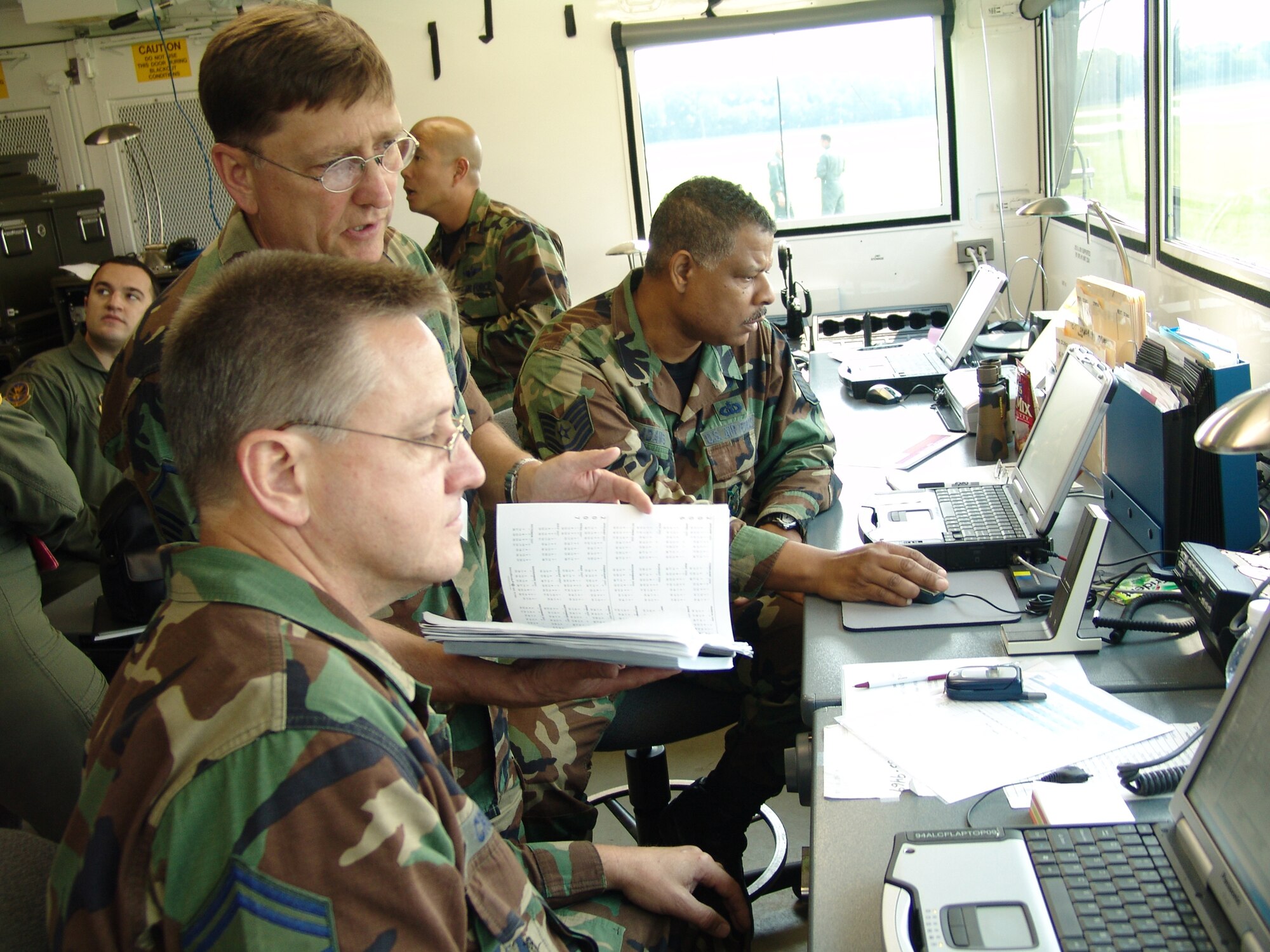 Master Sgt. Richard Lutz (center), 728th Airlift Squadron C-17 training loadmaster discusses flight information with Senior Master Sgt. Steve Crook, 94th Airlift Control Element superintendant, while Tech. Sgt. Michael Adams, 94th Airlift Control Element controller examines flight information on his computer, as members of the 706th Provisional Contingency Response Element during Golden Medic 2007 at Augusta Regional Airport - Bush Field, Ga.
