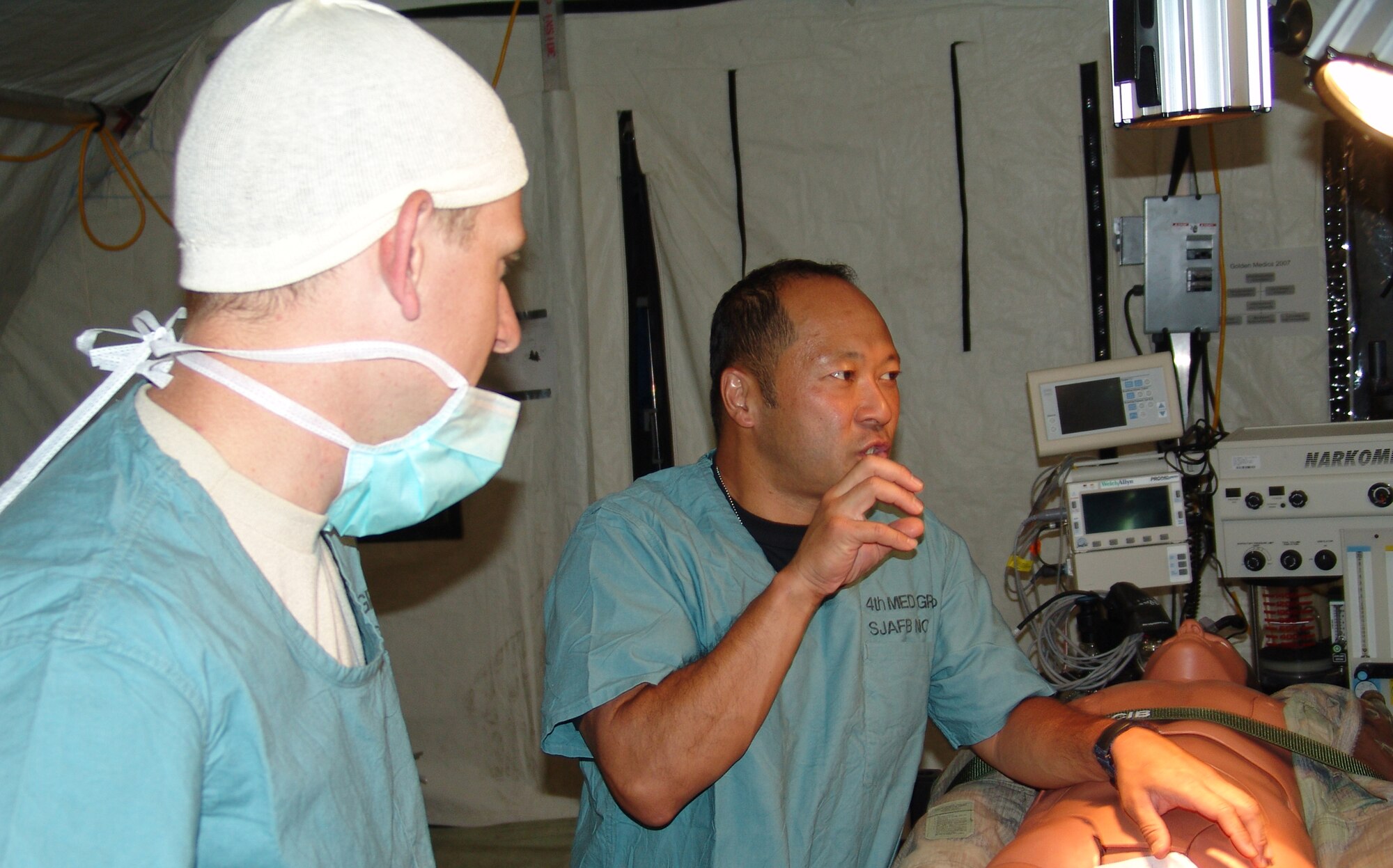 Lt. Col. Eric Ifune, 349th Medical Squadron, Travis Air Force Base, Calif., explains the proper procedures on performing surgery on a simulated patient at the Golden Medic 2007 exercise at Fort Gordon, Ga., June 16, as Sgt. Matthew Maress, 801st Combat Support Hospital operating room specialist, Illinois National Guard watches intently.