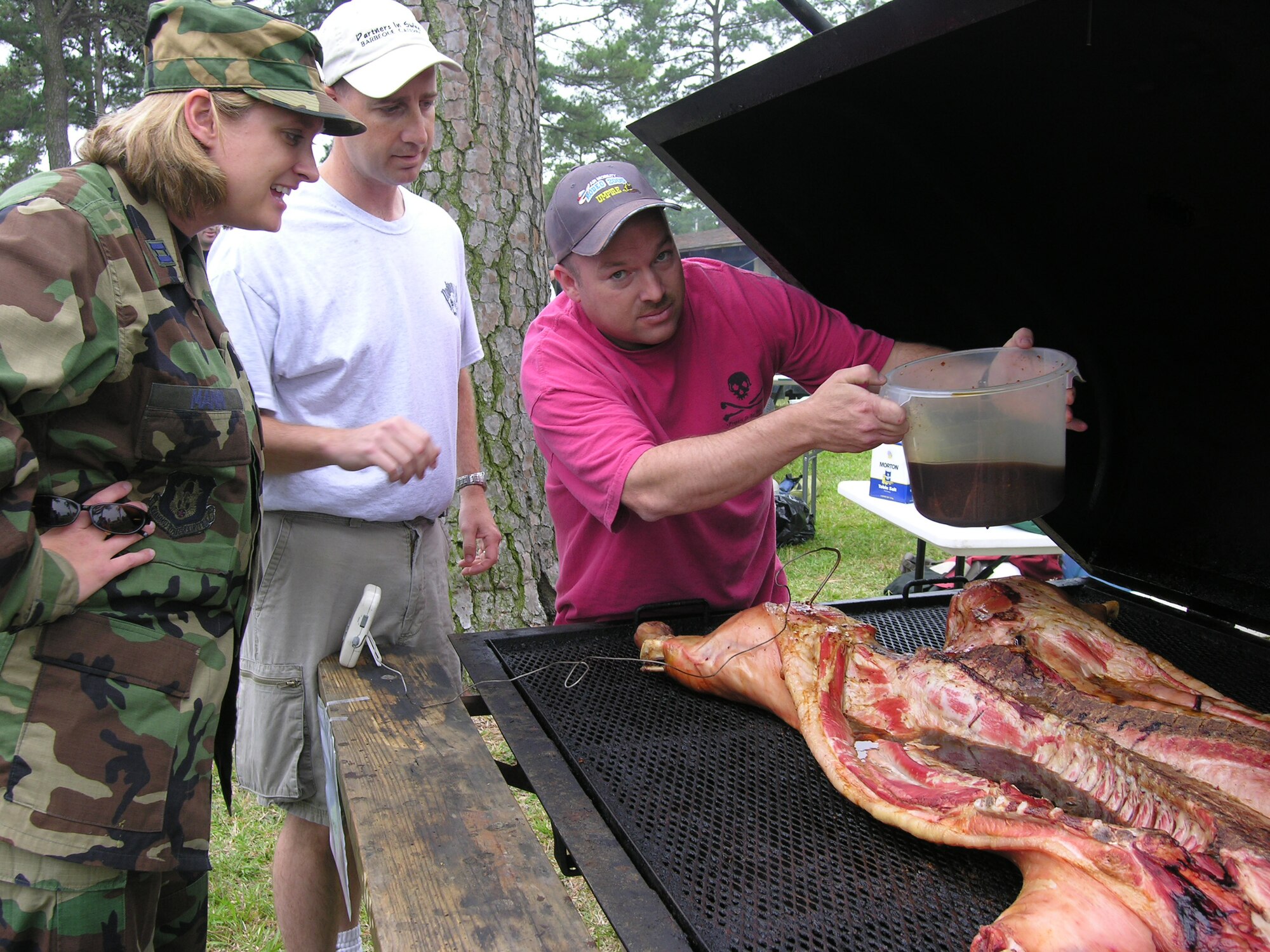 Seymour Johnson Air Force Base, N.C. -- Master Sgt. Chris Scher (right) and Master Sgt. Kevin Cameron (middle) represent the 916th Air Refueling Wing, Air Force Reserve, during a recent Eastern Carolina BBQ cook-off sponsored by the Seymour Johnson AFB Military Affairs Committee.  More than 10 teams started applying their 'secret' sauces at 5am on Thursday, June 14 in hopes of winning the taste buds of military members attending the appreciation event later that afternoon. Sgts. Scher and Cameron are members of the 916th Maintenance Group.