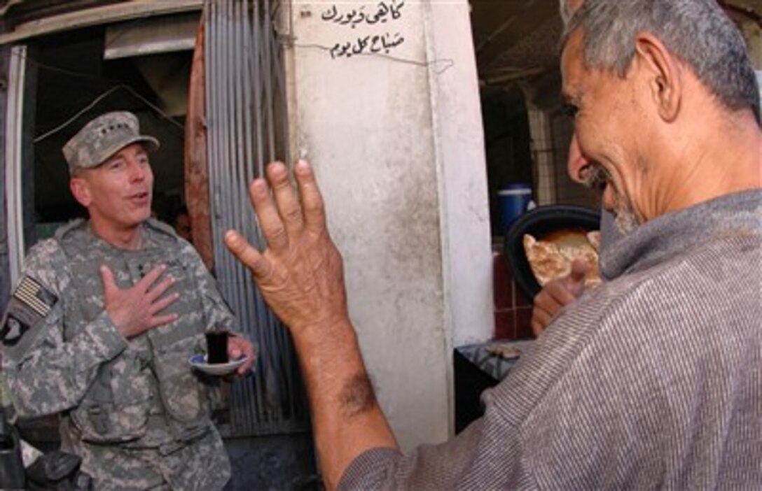 Commander of Multi-National Force - Iraq Gen. David H. Petraeus, U.S. Army, jokes with an Iraqi man over a cup of chai at a small cafe near the Al Saray book market in Baghdad, Iraq, on June 14, 2007.  Petraeus walked to the market to view the reconstruction progress after it was hit by a car bomb on March 5.  