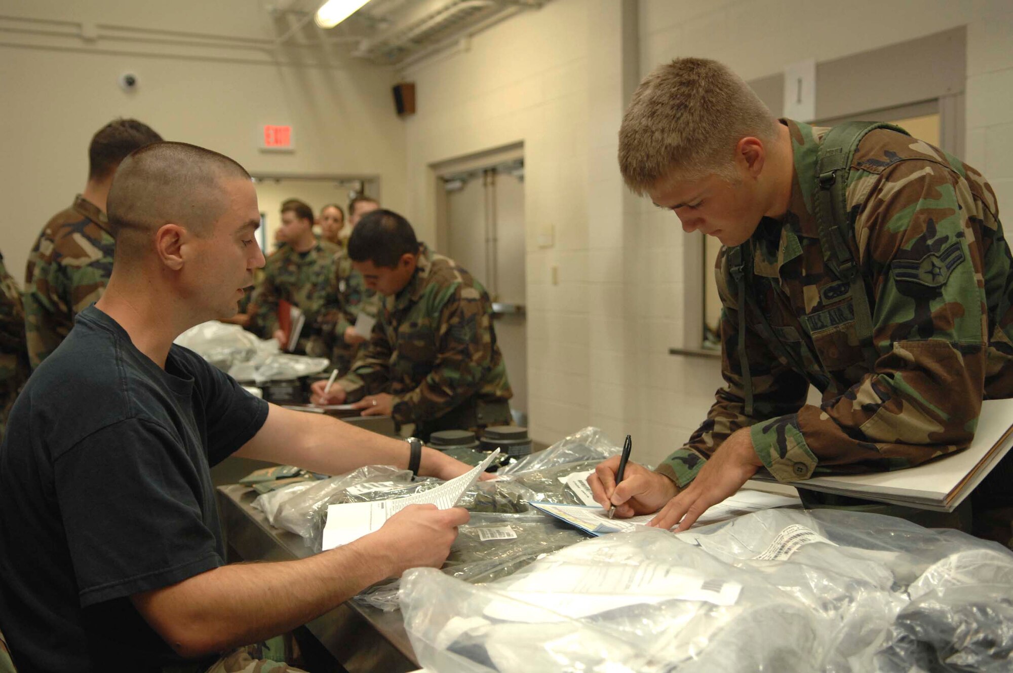 SHAW AIR FORCE BASE, S.C. -- Airman 1st Class Steven George (right), 20th Equipment Maintenance Squadron armament flight, signs for his chemical and biological personal protective equipment issued to him by Tech. Sgt. Frederick Rieger, 20th Contracting Squadron contracting specialist, during an operational readiness exercise June 18. Phase I exercises are an important because they allow the wing to assess large deployment capability in a controlled environment against a set standard.  (U.S. Air Force photo/ Tech. Sgt. Keri Whitehead)


