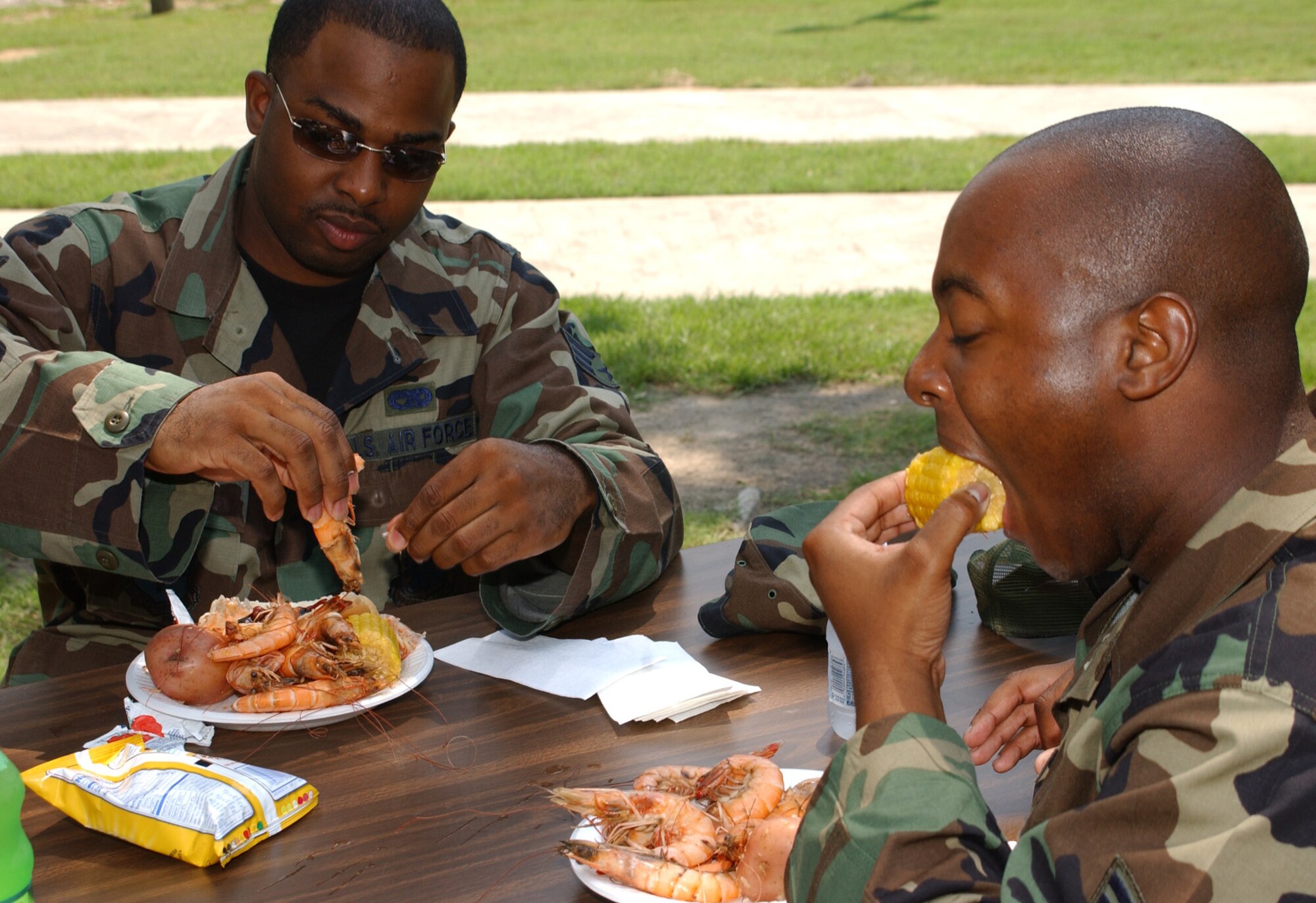 Above, Senior Airmen Leviticus Robinson, left, and Kendall Denson, 81st Transportation Squadron, enjoy boiled shrimp, potatoes and corn during Keesler’s 66th birthday celebration, June 14 in marina park.  (U. S. Air Force photo by Kemberly Groue)
