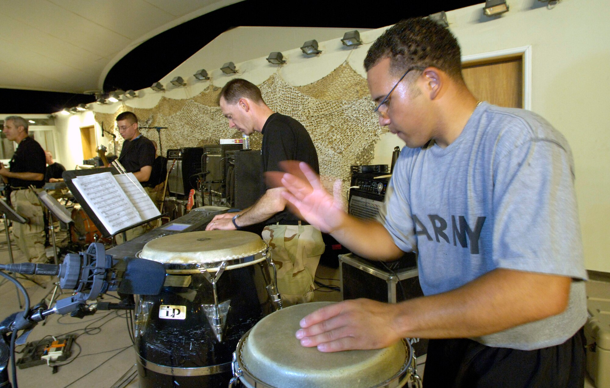 U.S. Army Spec. Jose Feurtado (right) sits in with the band. Two U.S. Central Air Forces expeditionary bands that debuted under their new names "Live Round" and "Thunder Roll" held a combined kick-off concert for deployed servicemembers June 16 at an air base in Southwest Asia.  Specialist Feurtado is an Abrams tank driver deployed to Baghdad, Iraq.  (U.S. Air Force photo/Master Sgt. Jim Varhegyi)