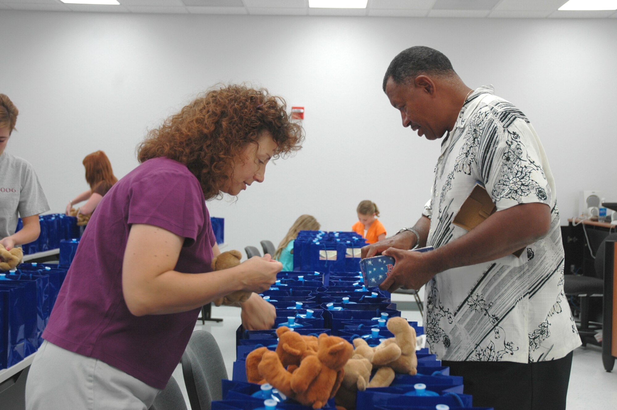 Lola Carrell, wife of 355th Mission Support Group Deputy Commander Lt. Col. David Carrell, and Clayton Moore, a community readiness technician at the Airman Family and Readiness Center here, fill care packages at the AFRC June 11.  First shirts, commanders, chaplains and squadron volunteers helped deliver the packages to families of deployed Airmen at their homes, kicking off D-M's Community Cares campaign.