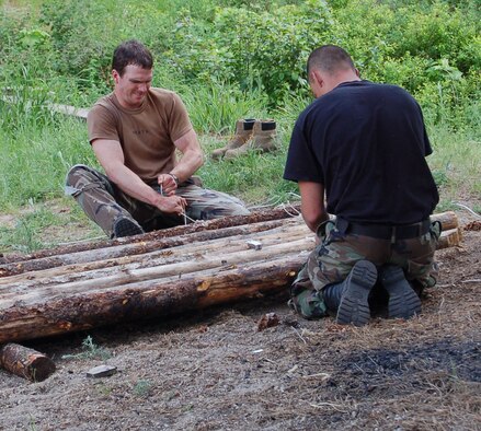 Senior Airmen Matthew Heath and Brian Tomlinson tie timber together to form a raft prior to crossing a pond with their gear June 12 during the 2007 SERE Challenge.  Both Airmen are assigned as Survival, Evasion, Resistance, Escape specialists at Fairchild AFB, Wash.  (U.S. Air Force photo by Staff Sgt. Matthew Rosine)