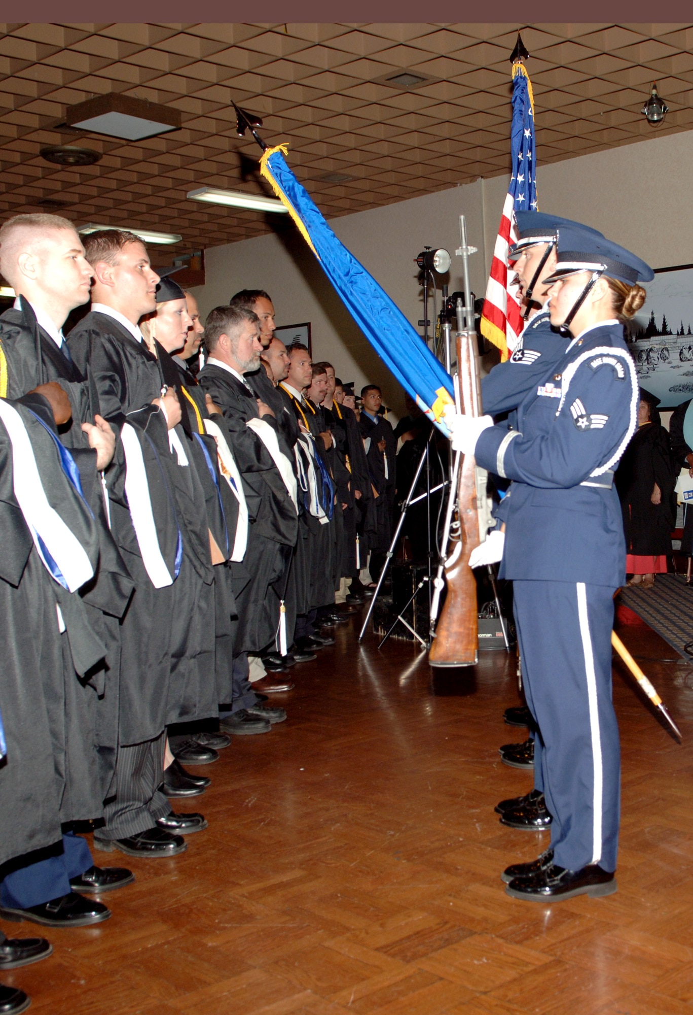 FAIRCHILD AIR FORCE BASE, Wash. – At the Fairchild Combined Commencement Ceremony June 15, graduates rise with their hands over their hearts as the base Honor Guard presents the colors. The Community College of the Air Force, Community Colleges of Spokane, Southern Illinois University, Park University, Embry-Riddle Aeronautical University and Webster University awarded 227 graduates with their degrees. (U.S. Air Force photo/Airman 1st Class Joshua Chapman)