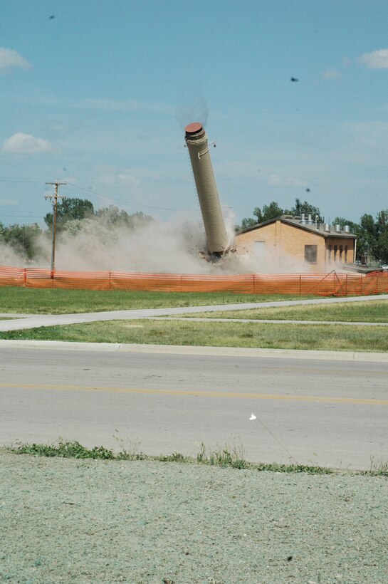 The chimney comes crashing down during the demolition June 16. Eight pounds of explosives were used to bring down this 55 year-old, 95-foot chimney. It is being demolished due to cracks discovered last month which threatened its stability. (U.S. Air Force photo/Airman Nathan Riley)