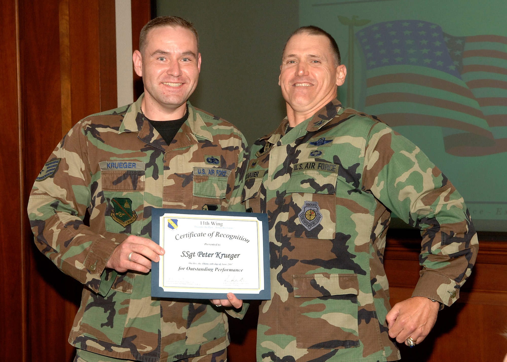 Staff Sgt. Peter Krueger displays certificate of recognition for his outstanding performance in the January 2007 UCI, while Col. Kurt F. Neubauer, 11th Wing commander, enjoys the moment at wing standup June 13. Colonel Neubauer also presented Sergeant Krueger with an 11th Wing coin in recognition of his impressive contributions to the Pentagon Military Personnel Flight mission. (U.S. Air Force photo by Thomas Dennis)
