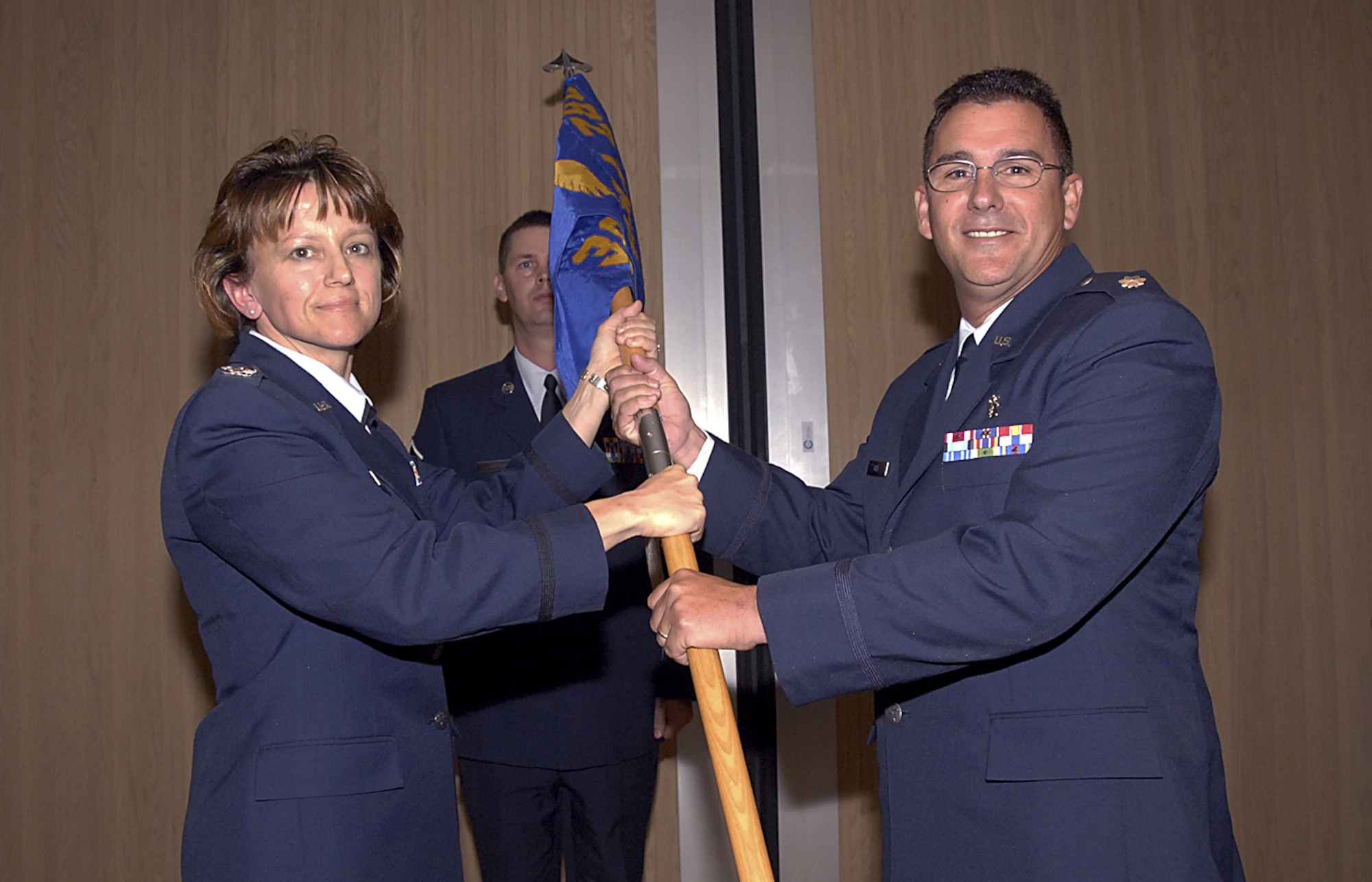 Col. Nancy Dezell, 882nd Training Group commander, hands the guidon to Lt. Col. Craig Rice, incoming 381st Training Squadron commander, June 18 at the 381st TRS change-of-command ceremony. (U.S. Air Force photo/Harry Tonemah)