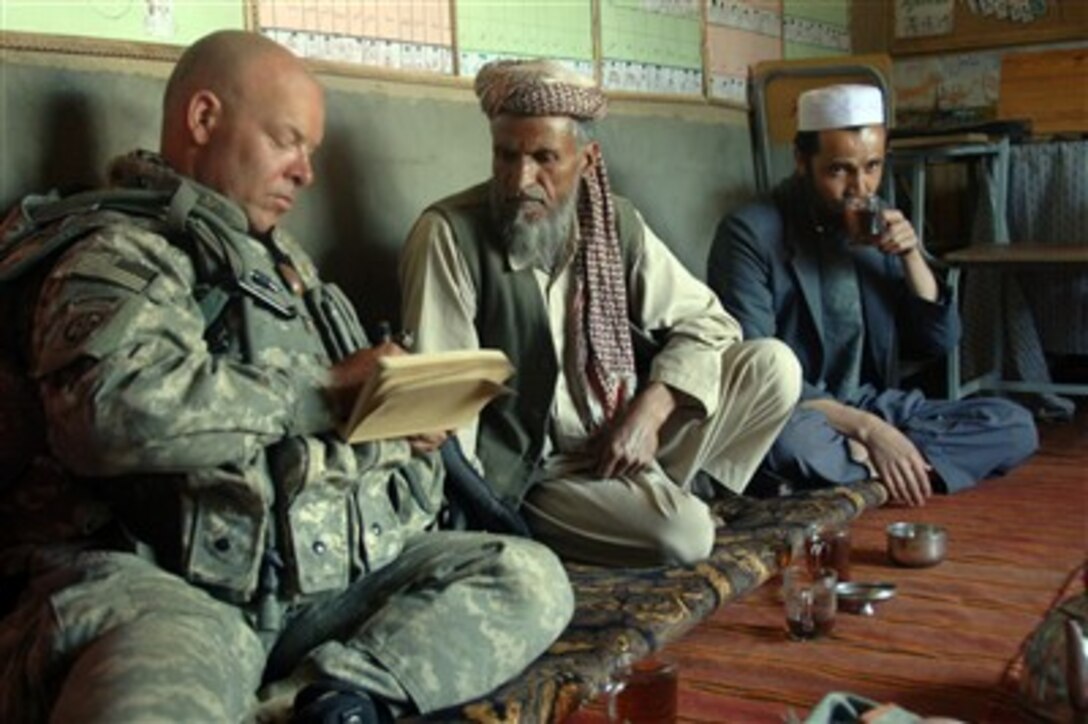 U.S. Army Maj. Robert Holbert takes notes as he talks and drinks tea with local school and Andar Special Needs School administrators during a cordon and search of Nani, Afghanistan, on June 2, 2007.  Holbert is attached to the Human Terrain Team, 4th Brigade Combat Team.  