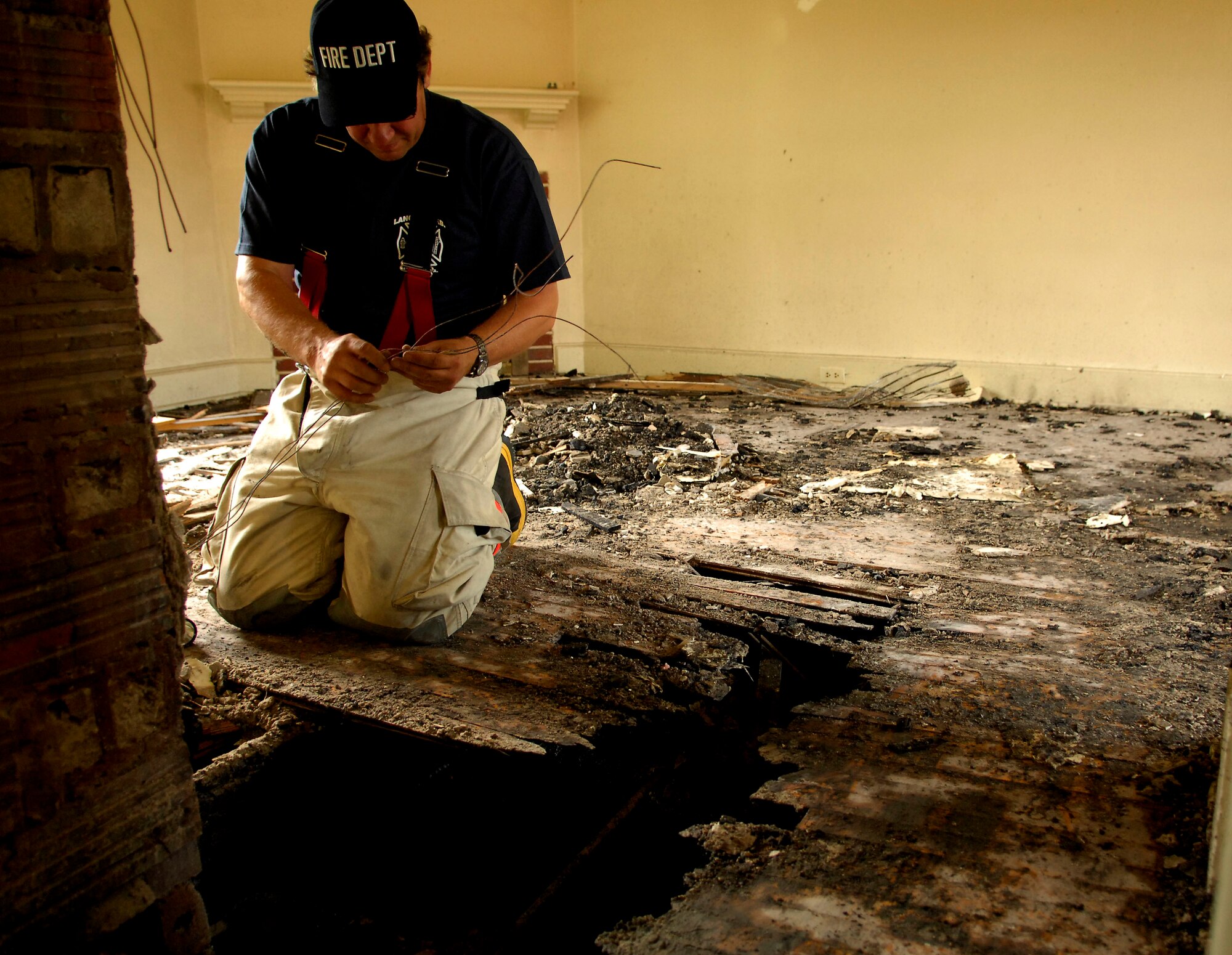 Frank Koninski, a firefighter with the 1st Civil Engineer Squadron Fire Department, investigates the structural damage of a vacant home to determine the cause of the fire, which occurred in the senior enlisted housing area here June 15. (U.S. Air Force Photo/Staff Sgt. Samuel Rogers)