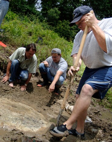 Mark Bunce, amateur fossil collector, Dave Cicimurri, curator of collections at the Campbell Geological Museum at Clemson University, Tech. Sgt. Richard Kaminsky, 437 CS NCO in charge of multimedia and amateur fossil collector and curator, clean off the top and sides of the 30 million-year-old leatherback sea turtle in the Saw Branch Canal in Summerville, S.C., June 14.(U.S. Air Force photo/Airman 1st Class Nicholas Pilch)

