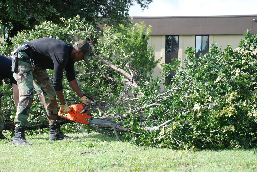 Airman 1st Class Alan Franklin, 82nd Civil Engineer Squadron, cuts into a fallen tree branch June 20 outside Bldg. 400. The 82nd CES, Sheppard fire and rescue services and 82nd Security Forces Squadron raced into action after thunderstorms assaulted Sheppard with 85 mph winds. Electricity was knocked out across base, but was quickly restored. (U.S. Air Force photo/Victoria Brayton)