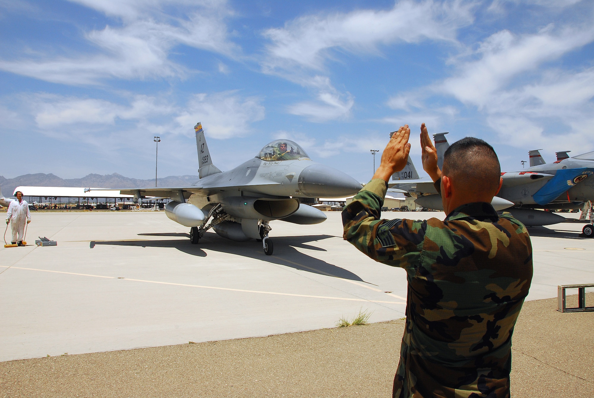 Staff Sgt. Michael Brizuela marshals the last operational F-16A model Fighting Falcon in the Air Force into a parking spot at Davis Monthan Air Force Base, Ariz.  The aircraft is being retired by the Arizona Air National Guard's 162nd Fighter Wing which now flies the more modern F-16C and F-16D models.  This aircraft and two F-16Bs being retired will be stored at the Aerospace Maintenance and Regeneration Group at Davis-Monthan.  (U.S. Air Force photo/Master Sgt. David Neve)