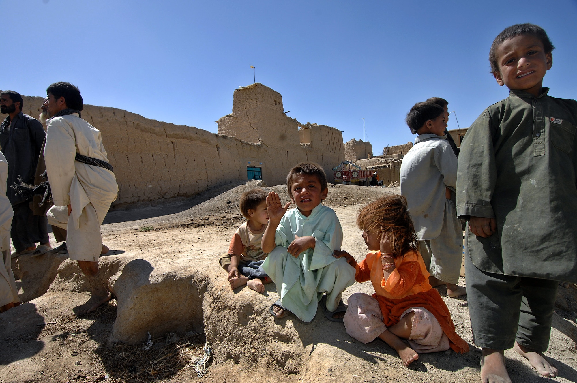 A group of children awaits a delivery of humanitarian supplies being delivered to the village of Qal' ehey Yuzbashi in Afghanistan. Lt. Gen. John Bradley, the Air Force Reserve Command commander and chief, was delivering the supplies to the village located near Bagram Air Base. The supplies, destined for refugee camps, orphanages and hospitals throughout Southwest Asia, are part of the 9,000 pounds collected by General Bradley's wife, Mrs. Jan Bradley. General Bradley is visiting Airmen throughout Southwest Asia to thank them for their service supporting the war on terrorism. (U.S. Air Force photo/Tech Sgt. Rick Sforza)