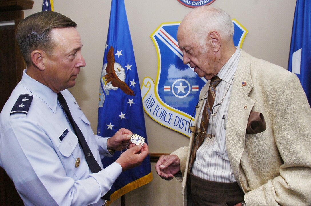 Air Force Maj. Gen. Robert L. Smollen, Air Force District of Washington commander, presents retired Col. Eugene P. Deatrick with his personal coin for his service in the Air Force. Deatrick was an Air Force pilot during the Vietnam conflict. While on assignment in Laos in 1966, Deatrick and his wing man discovered a SOS distress signal from downed Navy pilot, Dieter Dingler, and called for a rescue helicopter to pick him up. (U.S. Air Force photo by Bobby Jones)