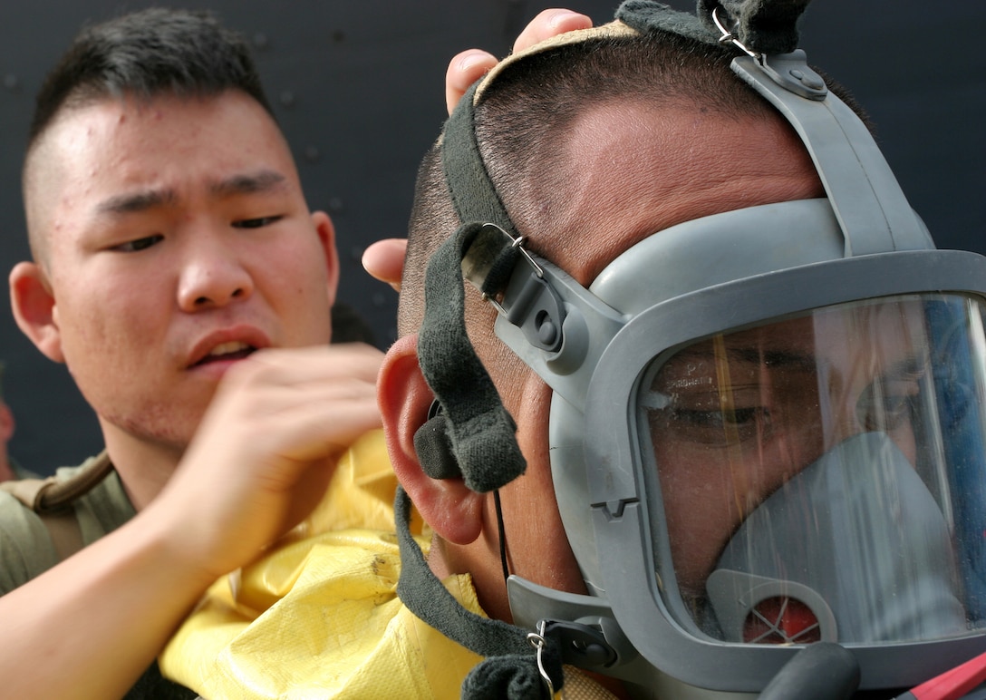 NAVAL AMPHIBIOUS BASE CORONADO, SAN DIEGO?Lance Cpl. Daniel J. Yeam (left), from Chicago, tightens the straps on the mask of Lance Cpl. Javier Aguirre, from Vallejo, Calif., before entering the USS Tarawa to conduct a Vessel Boarding Search and Seizure mission June 19, here. Marines and sailors from Battery G, Battalion Landing Team 1st Battalion, 5th Marine Regiment, 11th Marine Expeditionary Unit, from here, took part in a three-week training exercise to provide the 11th MEU with a confined space, site exploitation capability that can respond to a chemical, biological, radiological or nuclear incident. Yeam is a CBRN defense specialist and Aguirre is a field wireman with BLT 1/5, 11th MEU.