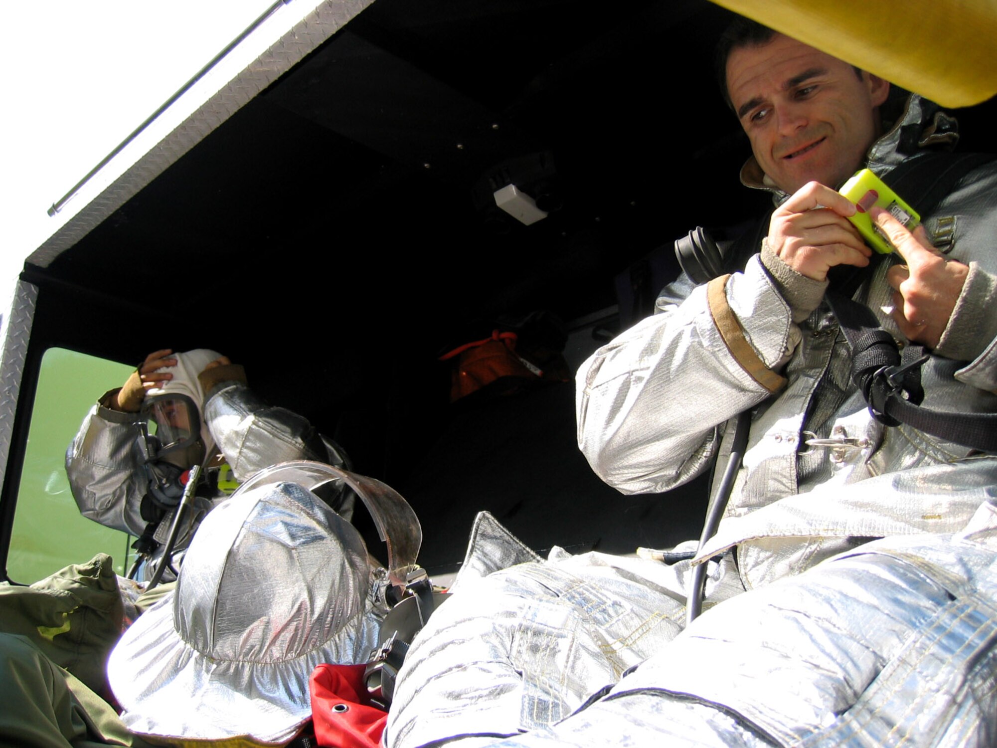 Airman 1st Class Noel Magtanong (left) and Portuguese firefighter Paulo Azera don their gear in the back of a fire truck on their way to a flight line exercise June 21 at Lajes Field, Portugal. Portuguese and American firefighters routinely work together to save lives and property. (U.S. Air Force photo/Airman 1st Class Shannon Ofiara) 