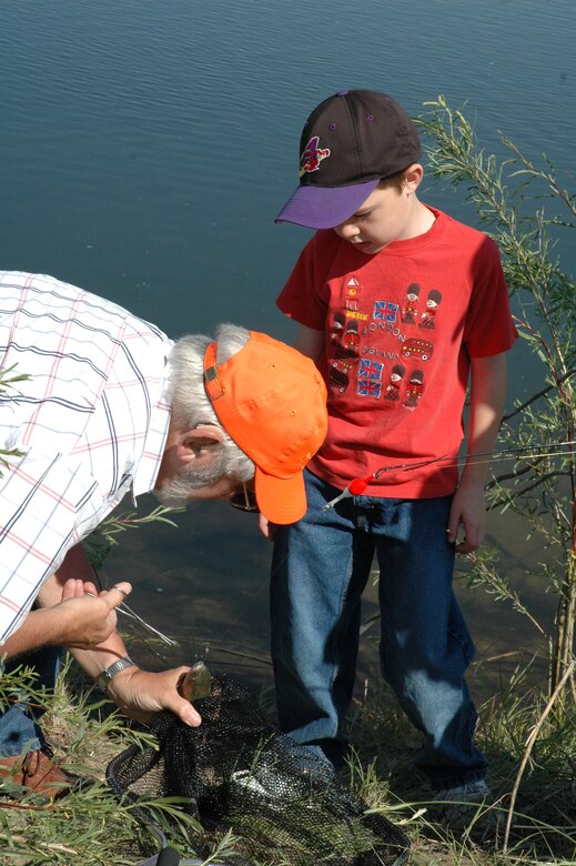 Little Warrior Jakob, 8, gets a helping hand from his grandfather to get his hook out of a trout duirng the 2nd Annual Kid's Fishing Day Saturday at Pow Wow Park. It was Jakob’s first catch of the day. (U.S. Air Force photo/Senior Airman Eydie Sakura)
