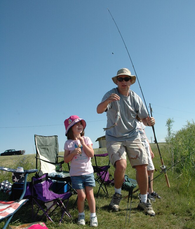 Little Warrior Kaitlyn, 5, gets assistance from her dad, Jeff, after catching the first fish at the 2nd Annual Kid’s Fishing Day event Saturday at Pow Wow Park. (U.S. Air Force photo/Senior Airman Eydie Sakura)