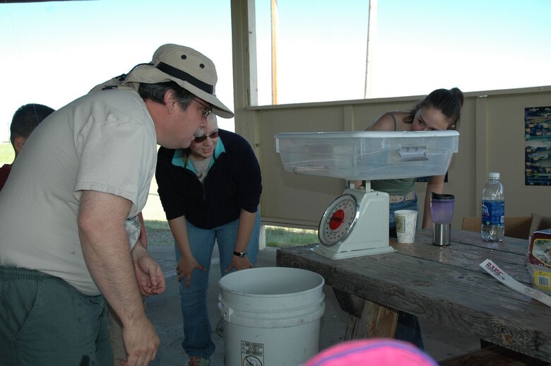 Don Delorme, 341st Civil Engineer Squadron solid waste program manager, and event volunteers, weigh the first catch of the day at the 2nd Annual Kids Fishing Day Saturday at Pow Wow Park. The trout weighed a quarter pound and went to Little Warrior Kaitlyn, 5.  (U.S. Air Force photo/Senior Airman Eydie Sakura)
