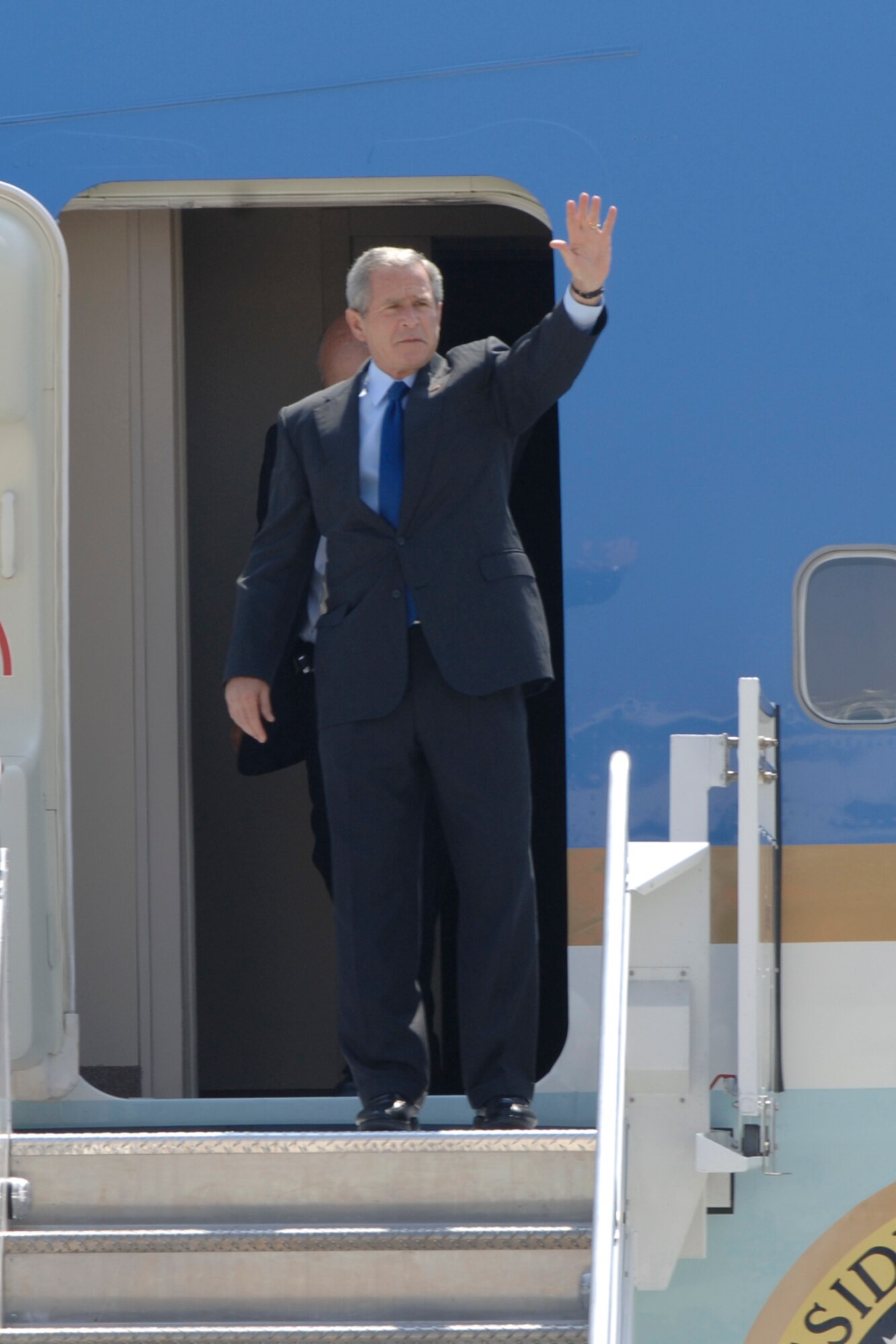 President George W. Bush waves to onlookers as he steps out of Air Force One at the McConnell Air Force Base Boeing Aircraft Plant runway in Wichita June 15. The president visited the Boys and Girls Club of South Central Kansas and attended a political fundraiser before heading on to Crawford, Texas. (Photo by Senior Airman Jamie Train)
