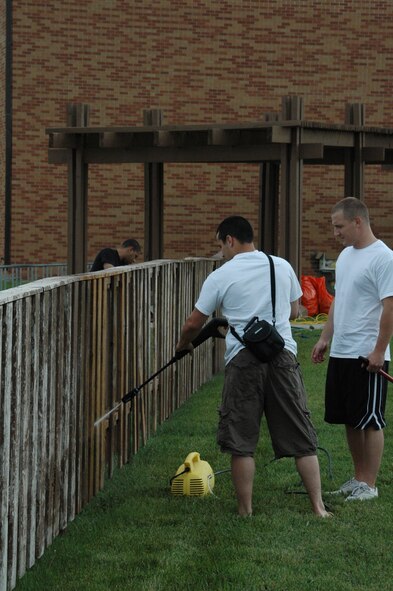 Senior Airman Luca Sabatini-Grace, 28th Maintenance Squadron and Senior Airman Christopher Helenek, 28th Aircraft Maintenance Squadron pressure wash the fence of the Bellamy Fitness Center playground here, June 15. Each Airman Leadership School class takes on a class project that will give back to the base or community. Class 07-6 chose to clean up this base playground. Class 07-6 is scheduled to graduate June 25 at the Dakotas. (U.S. Air Force photo/Tech. Sgt. Todd Wivell)