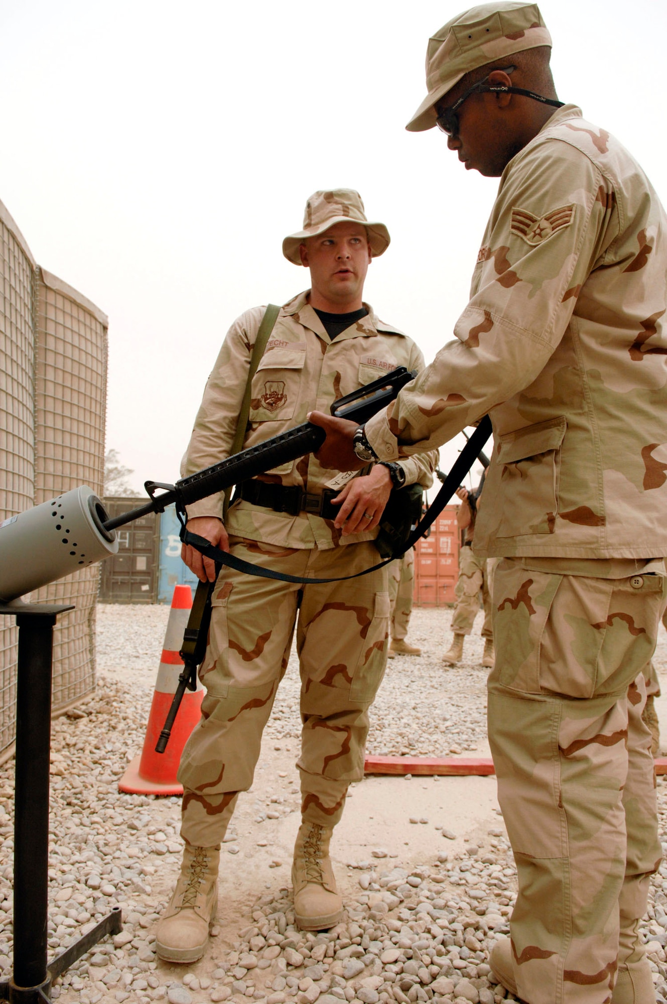Tech. Sgt. Steven Pecht (left) reviews clearing procedures for the M-16 rifle with Senior Airman Alexander Davis during a base-wide arming exercise June 14 at Ali Air Base, Iraq. Both are members of the 407th Expeditionary Communications Squadron. Ali AB Airmen participated in the exercise to help fine-tune weapons distributing procedures in case of a real-world threat to the base. (U.S. Air Force photo/Master Sgt. Robert W. Valenca) 
