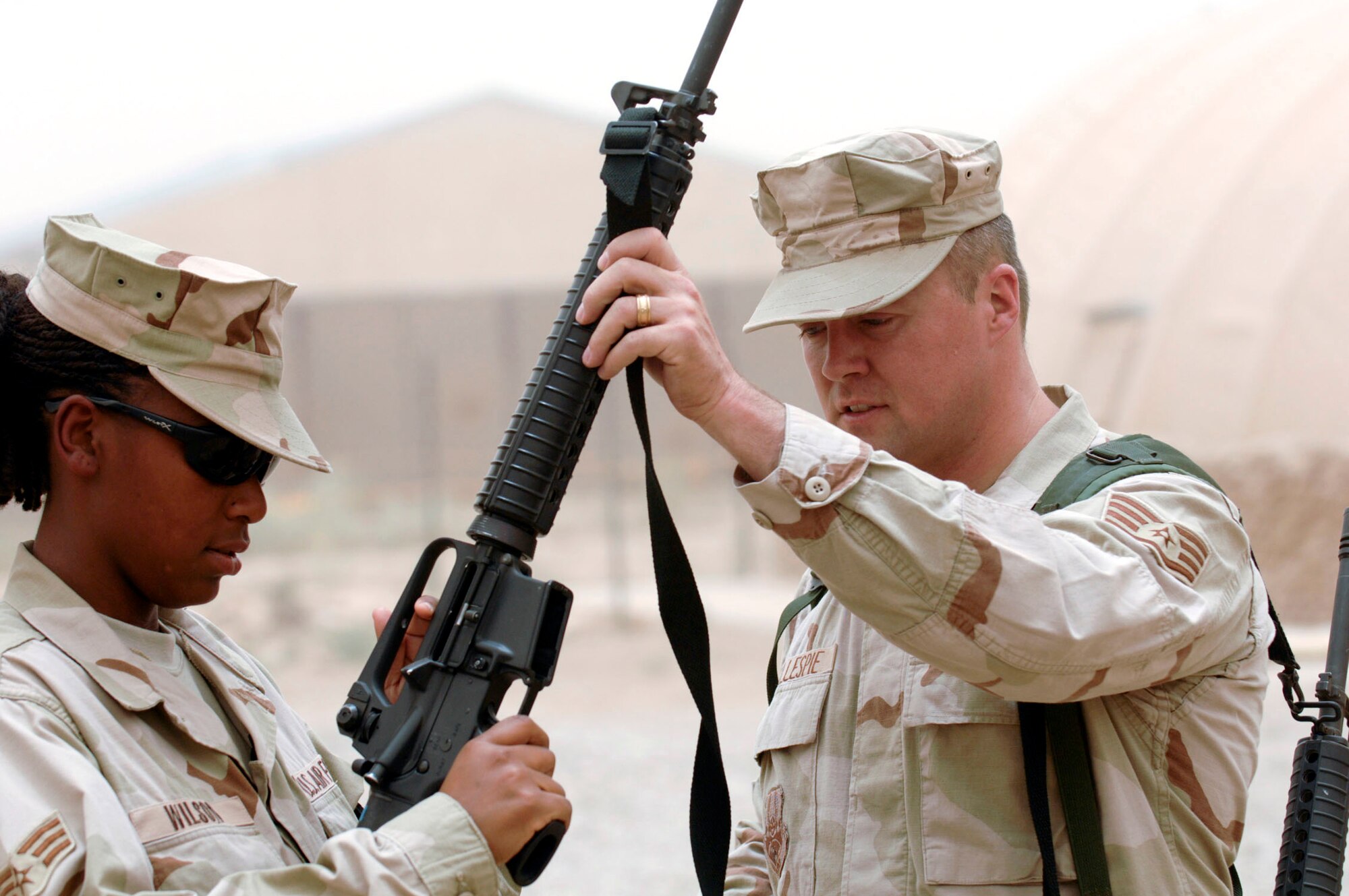 Staff Sgt. Allan Gillespie passes Senior Airman Ashley Wilson her M-16 rifle during a base-wide arming exercise June 14 at Ali Air Base, Iraq. Both are members of the 407th Expeditionary Communications Squadron. Ali AB Airmen participated in the exercise to help fine-tune weapons distributing procedures in case of a real-world threat to the base. (U.S. Air Force photo/Master Sgt. Robert W. Valenca) 

