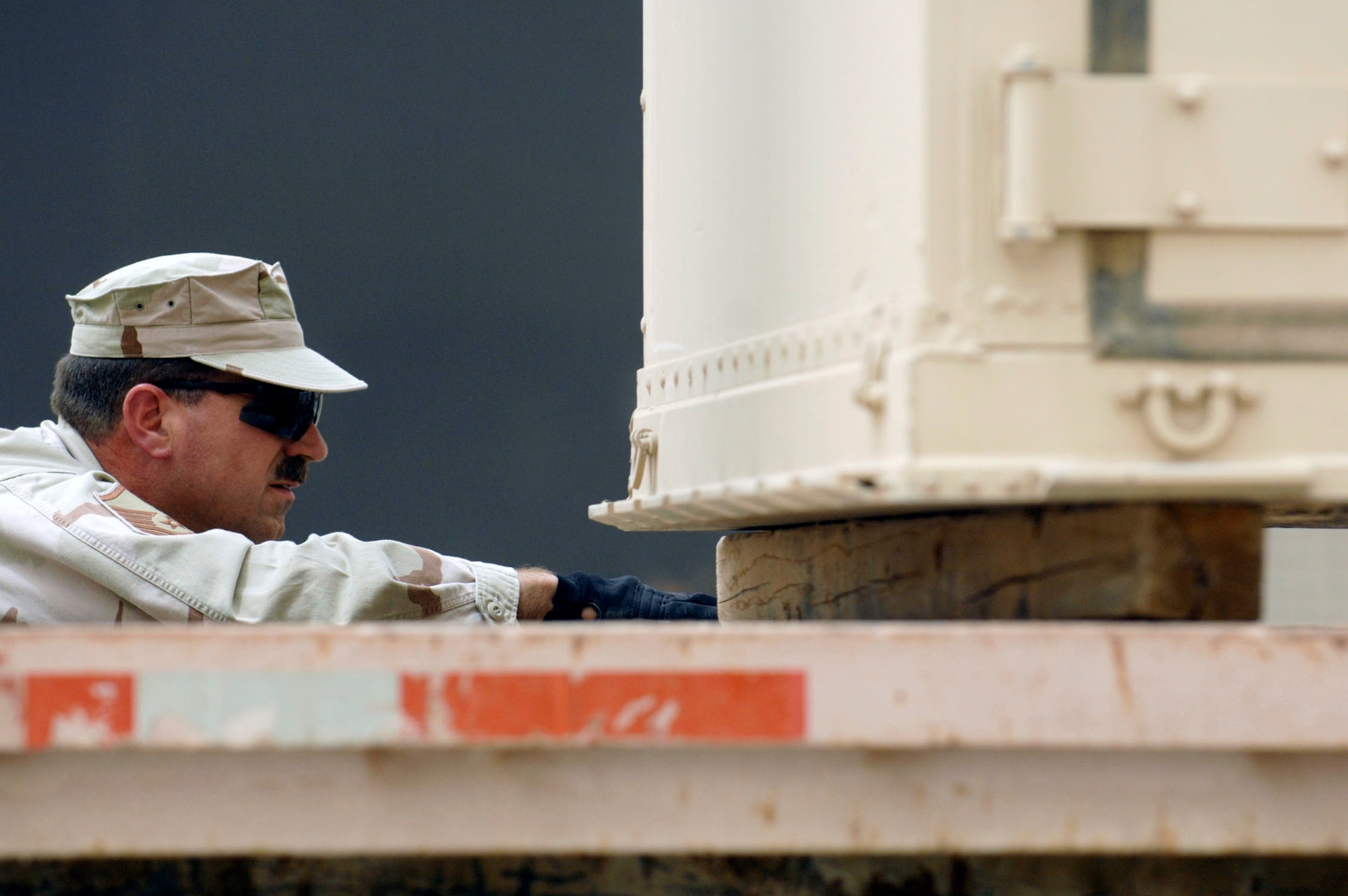 Master Sgt. Steven Anderson checks to ensure a container full of M-16s are sitting correctly on a trailer during a base-wide arming exercise June 14 at Ali Air Base, Iraq. Ali AB Airmen participated in the exercise to help fine-tune weapons distributing procedures in case of a real-world threat to the base. Sergeant Anderson is assigned to the 407th Expeditionary Logistics Readiness Squadron. (U.S. Air Force photo/Master Sgt. Robert W. Valenca) 
