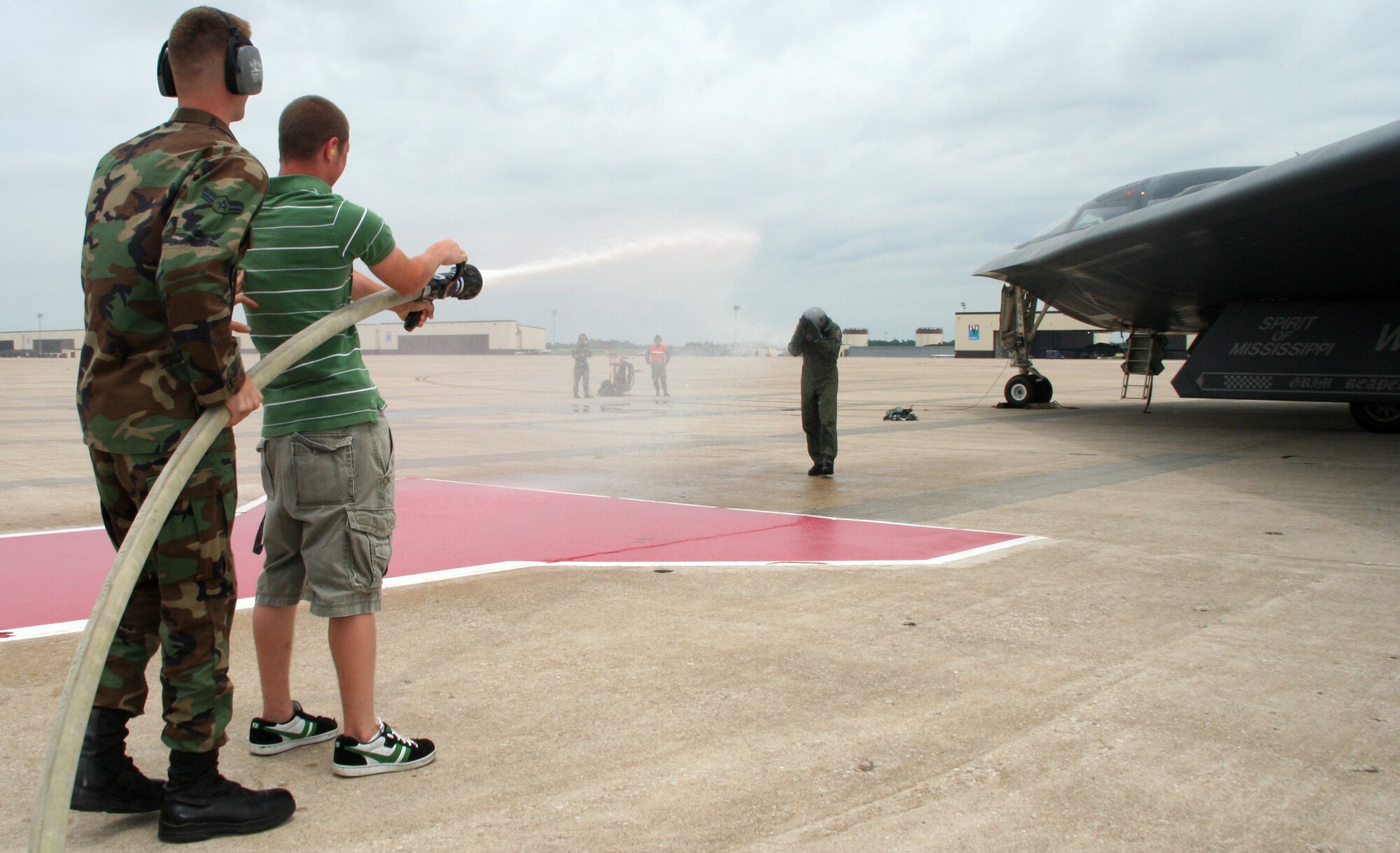 Sean Single, son of Col. Eric Single, 509th Bomb Wing vice commander, receives help from Airman 1st Class Lorenzo Lancia, 509th BW fire department, to spray the colonel following his last B-2 flight as vice commander June 20. (U.S. Air Force Photo/Airman 1st Class Stephen Linch)