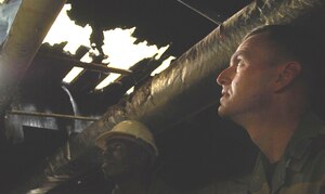 Master Sgt. Troy Thompson, a firefighter with the 1st Civil Engineer Squadron Fire Department, shows Col. Brian Yolitz , 1st Mission Support Group commander, the structural damage of a vacant home, which caught fire in the senior enlisted housing area here June 15. (U.S. Air Force Photo/Staff Sgt. Samuel Rogers)