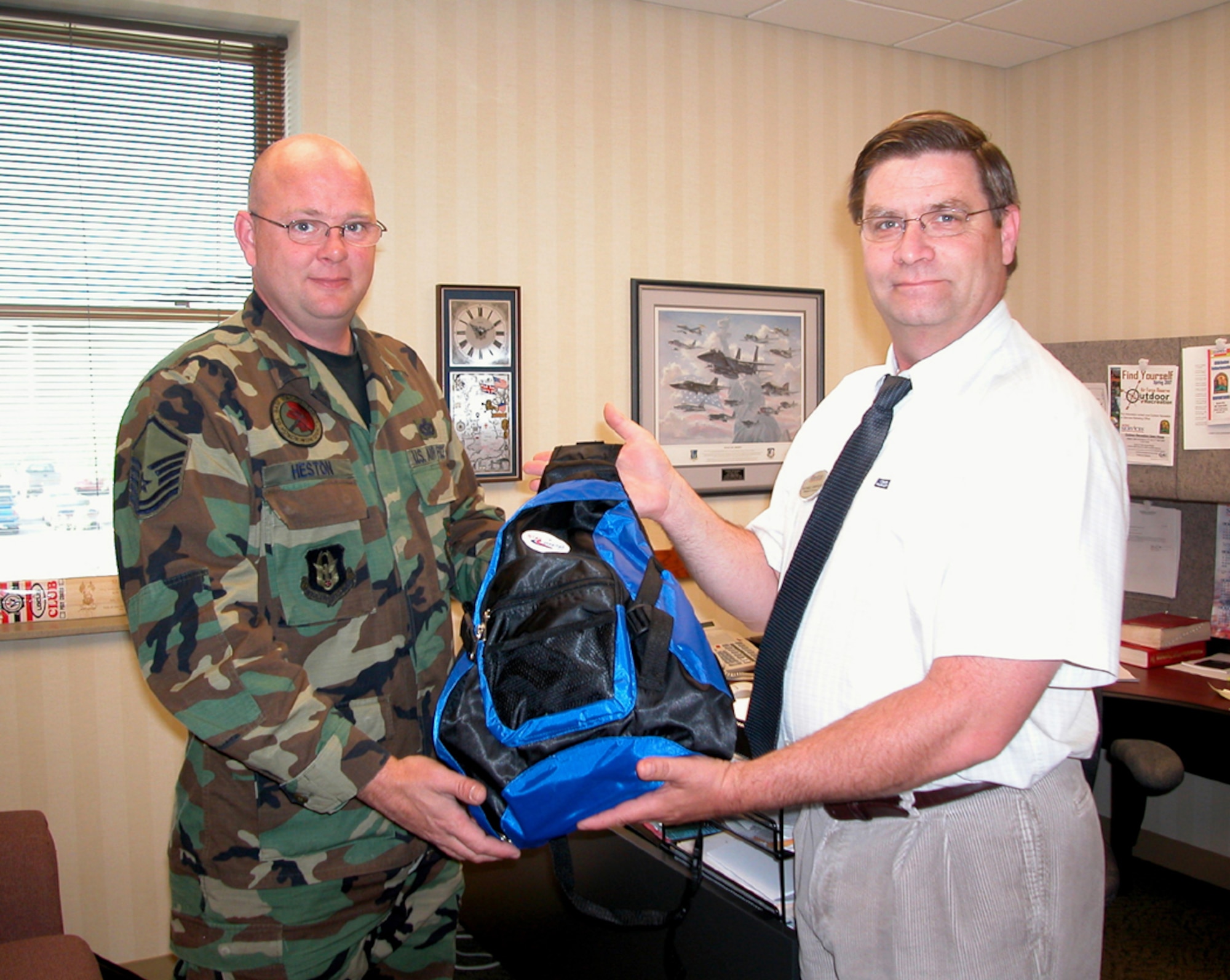 GRISSOM AIR RESERVE BASE, Ind., -- Mike Sampson, right, the services director and individual in charge of the 'Keep Connected Backpack' program, gives the first two backpacks to Master Sgt. Chris Heston, a utilities journeyman with the 434th Civil Engineering Squadron. He is deploying and is getting the packs for his two sons Clay and Christopher. (U.S. Air Force photo/SrA. Benjamin Mota)