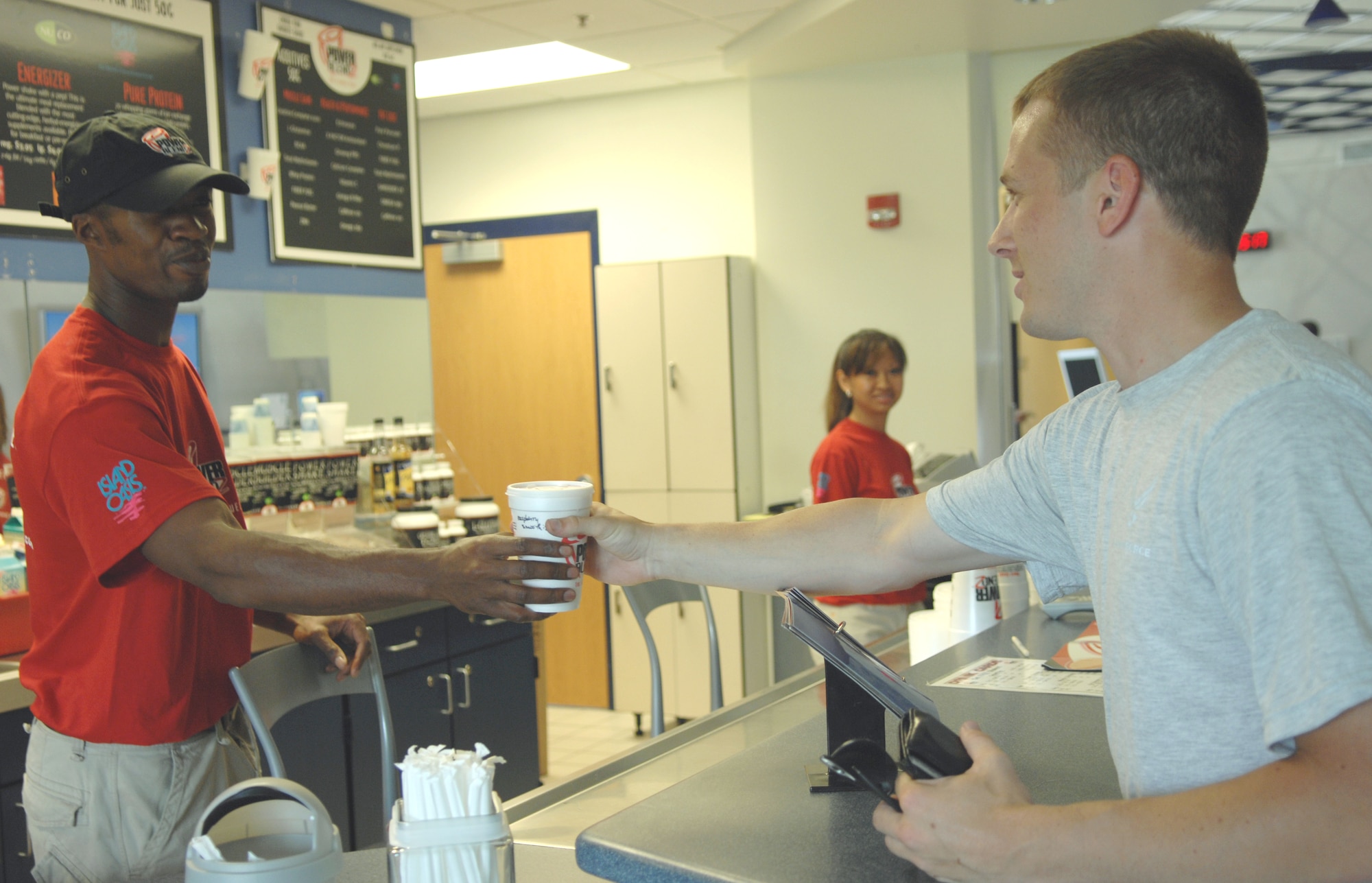 Owners Sophea and Kevin Moore prepare a shake for Staff Sgt. Justin Buske, 1st Equipment Maintenance Squadron munitions flight technician, in the newly reopened Power Blendz at the Shellbank Fitness Center here June 15. Power Blendz offers protein bars and snacks to maintain energy during a workout, while fruit smoothies and meal replacement shakes help Airmen maintain fitness goals after a workout. (U.S. Air Force photo/Senior Airman Tabitha Kuykendall)