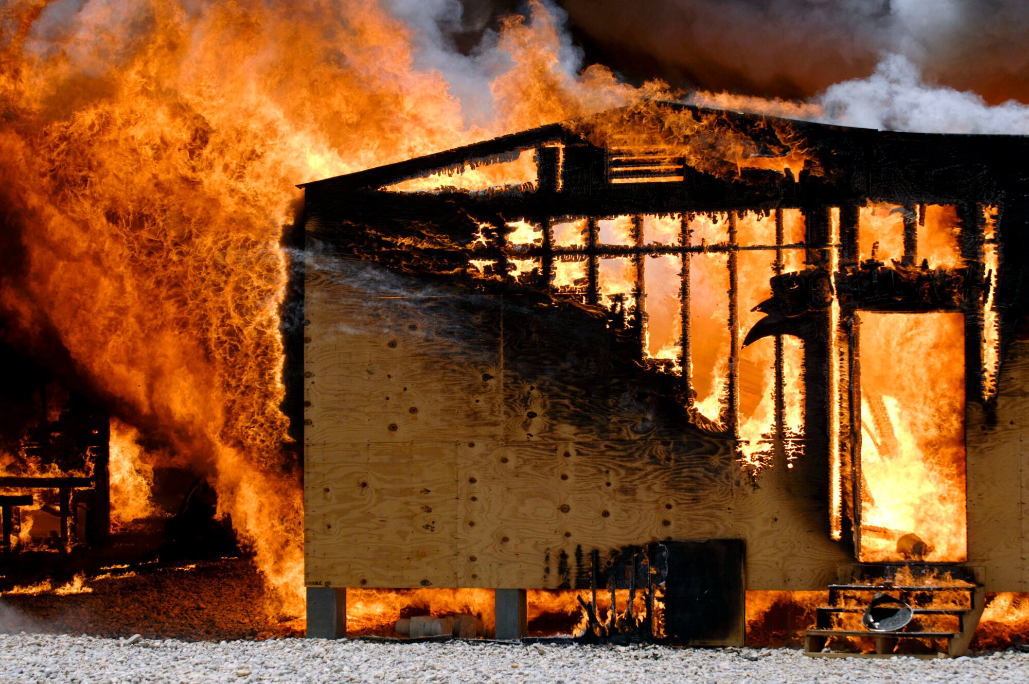 A fire burns out of control in the Army Motor Pool June 19 on Camp Adder, Iraq. Due to munitions contained in the building and no potential for loss of life, firefighters from the 407th Expeditionary Civil Engineer Squadron at Ali Air Base, Iraq, switched to defensive operations for the blaze using six trucks to keep it under control and confined to the building. (U.S. Air Force photo/Master Sgt. Robert W. Valenca)